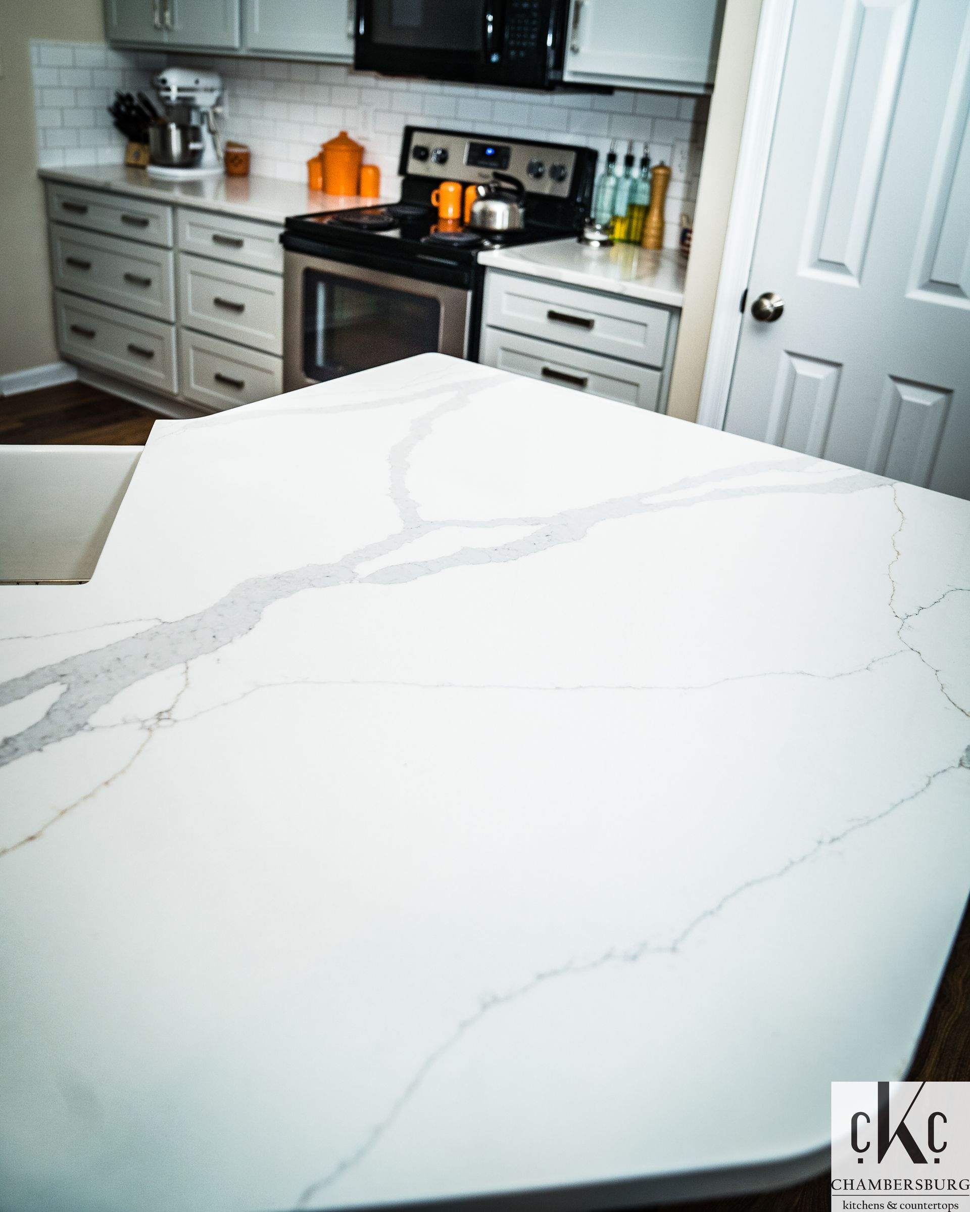 A kitchen with a large white counter top and a stove
