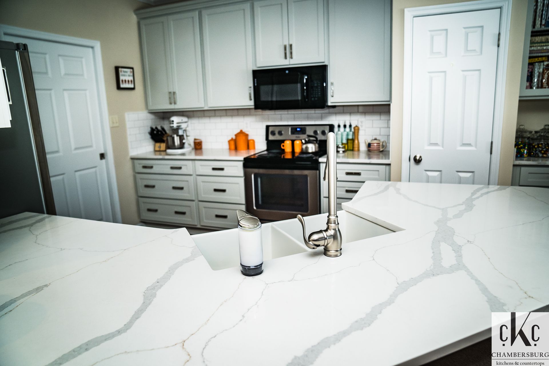 A kitchen with white cabinets, a sink, a stove and a microwave.