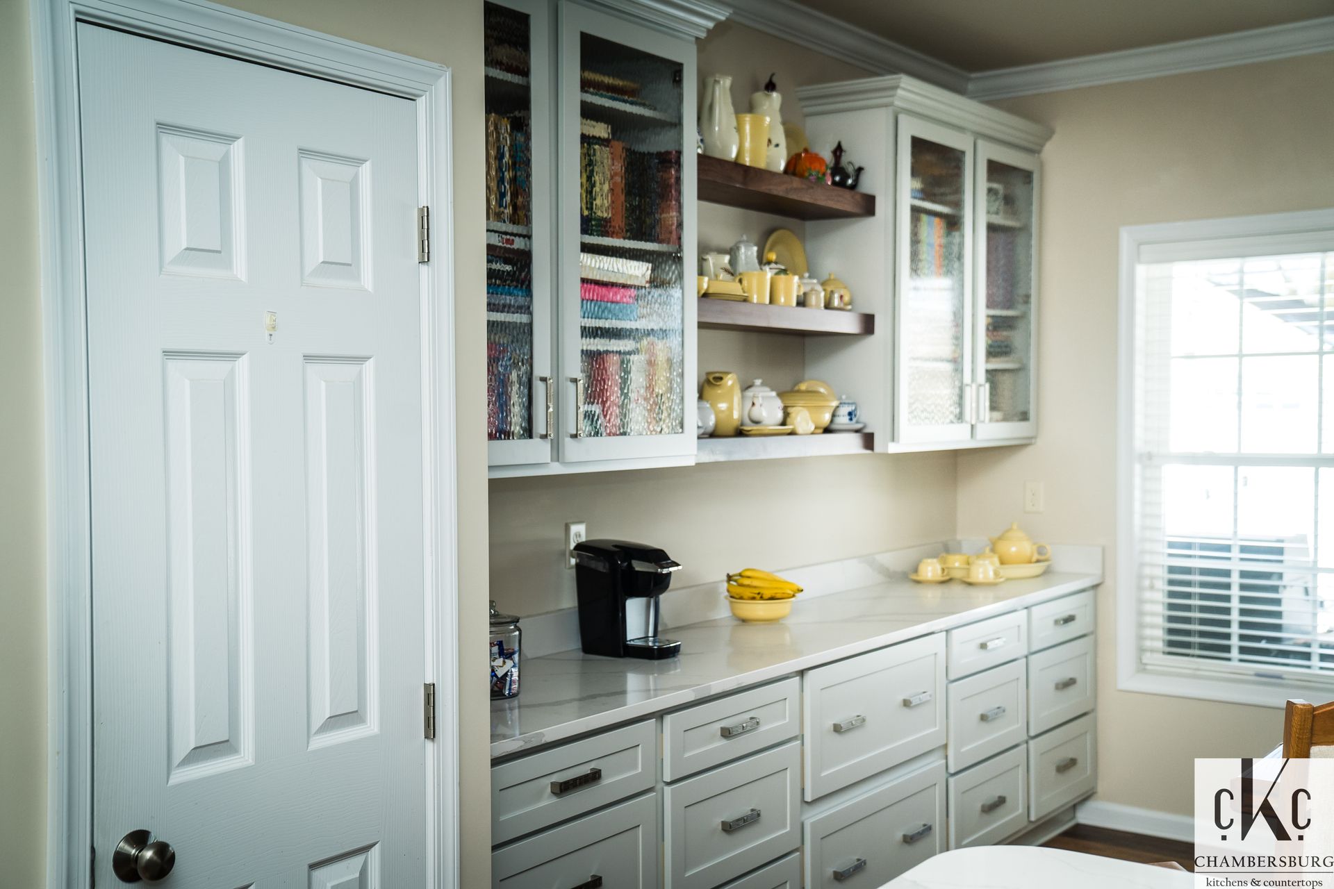 A kitchen with white cabinets and a coffee maker on the counter.
