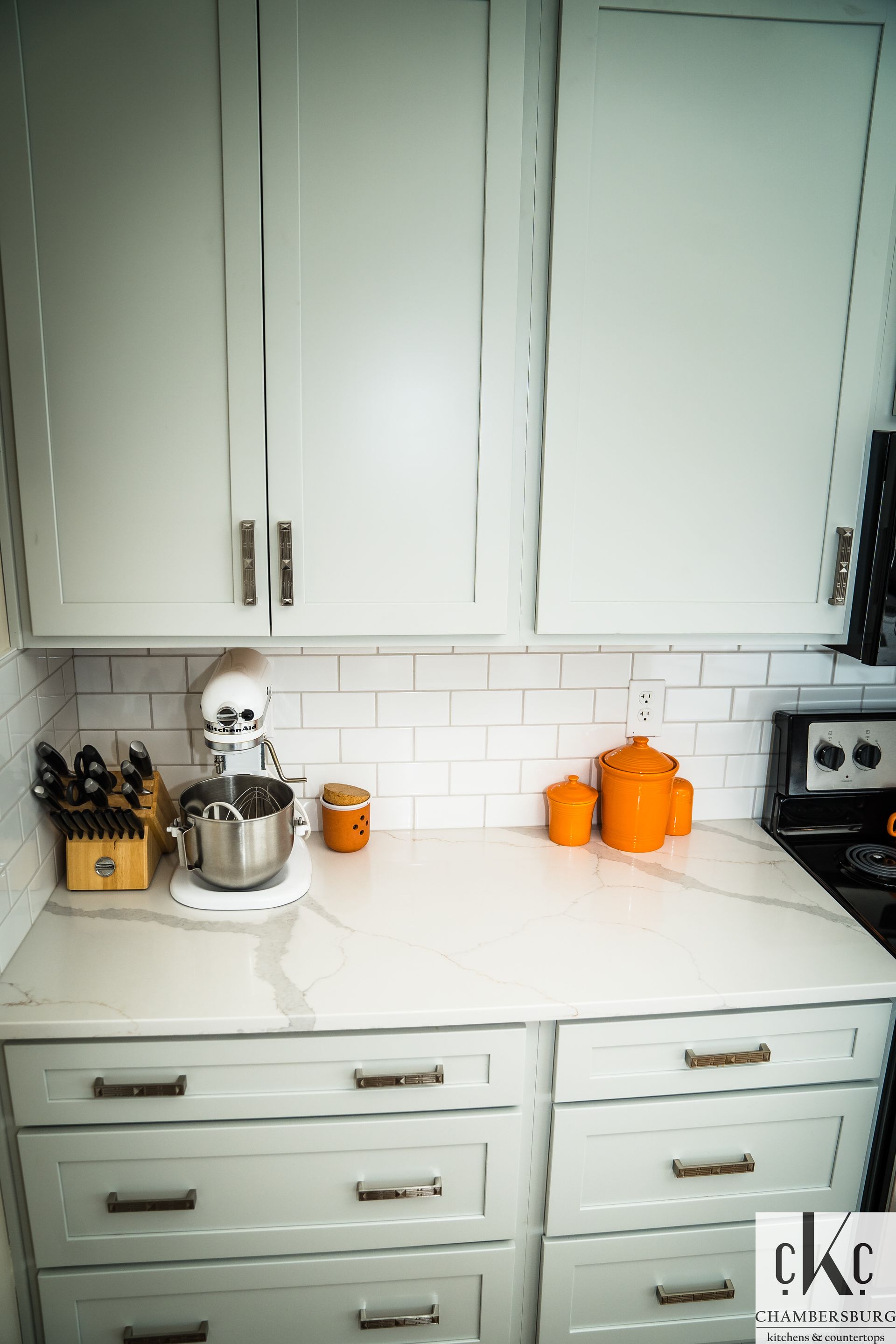 A kitchen with white cabinets and a mixer on the counter.