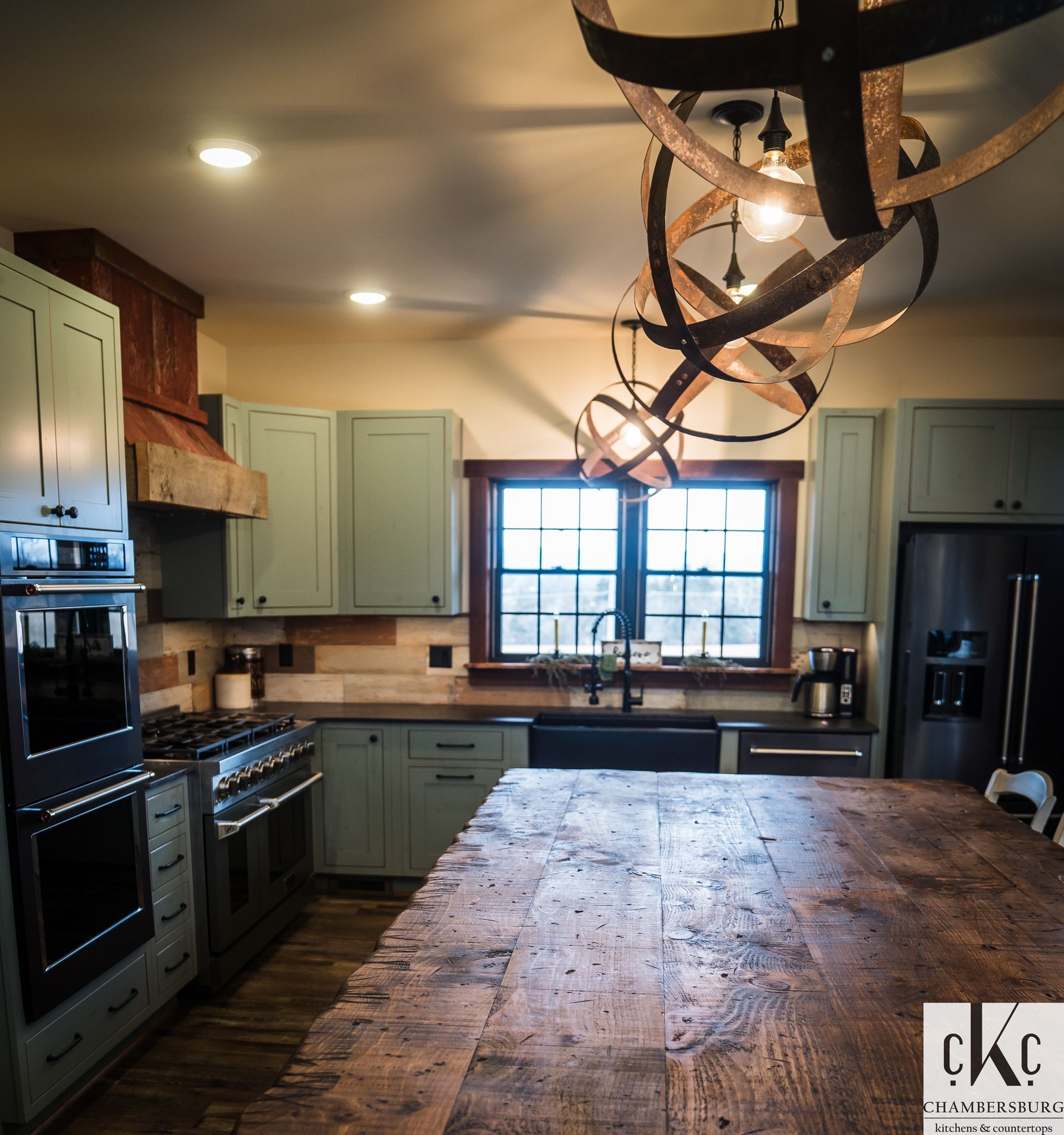 A kitchen with green cabinets and a large wooden table