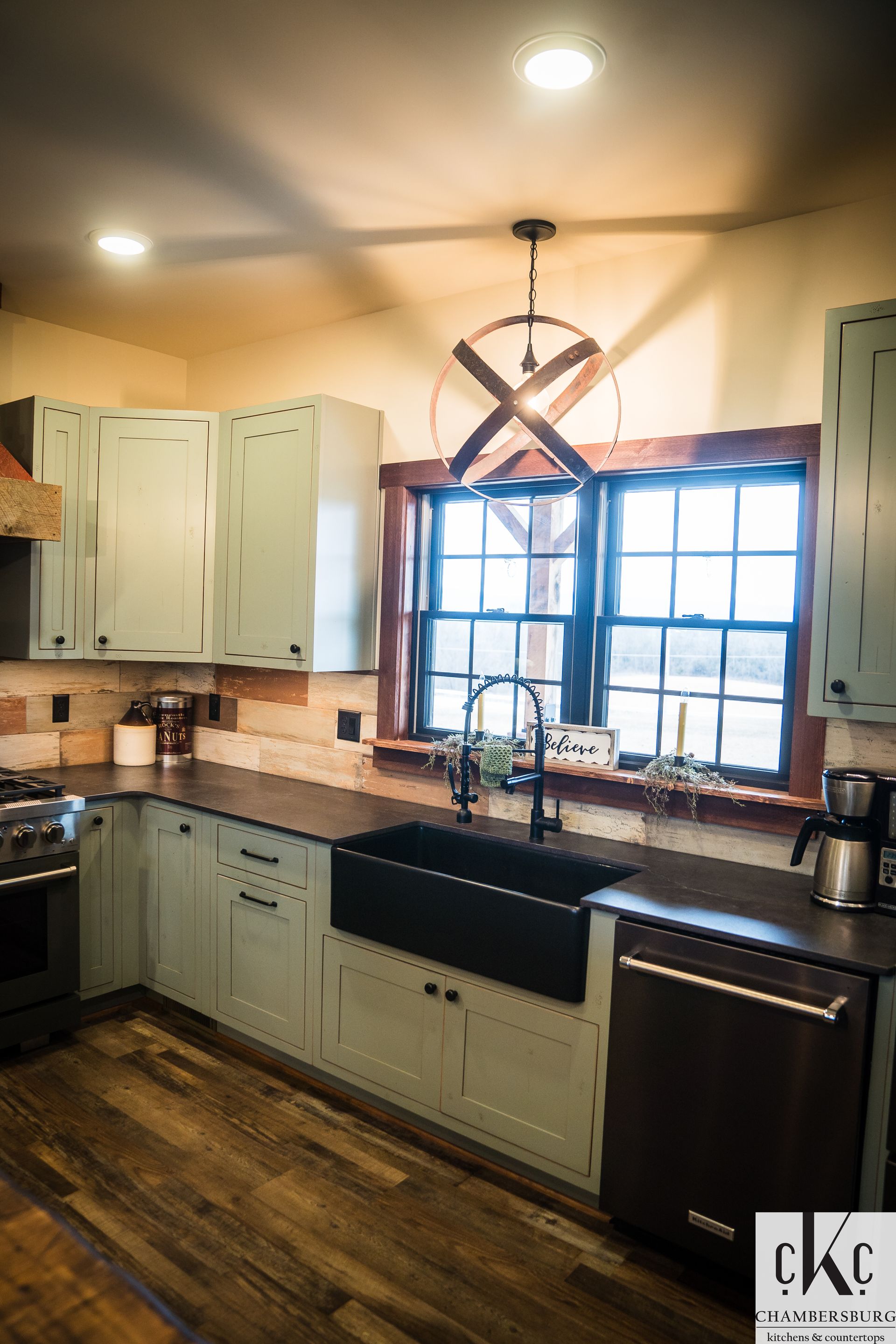 A kitchen with white cabinets, a black sink, a stove, and a window.