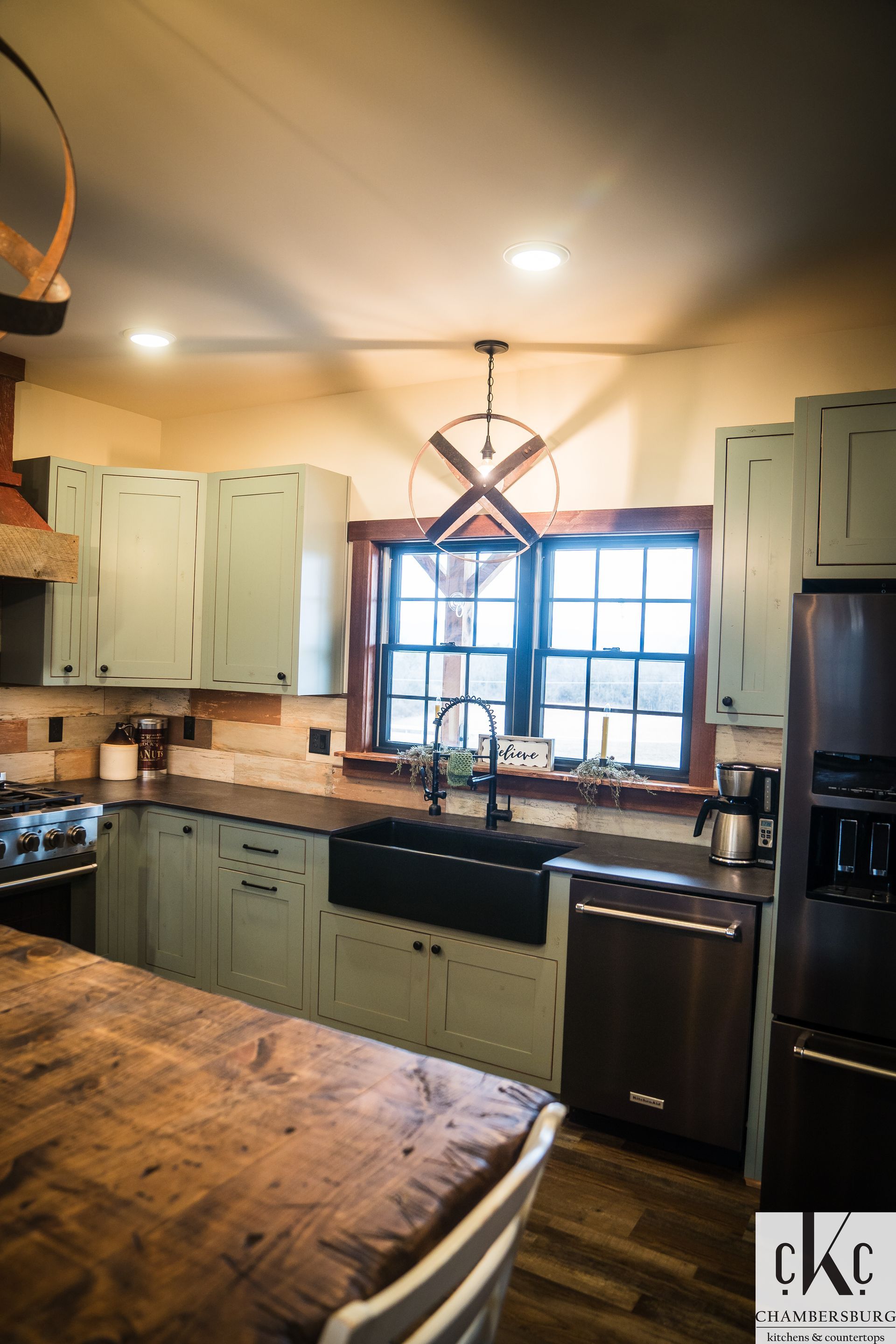 A kitchen with green cabinets and a black sink