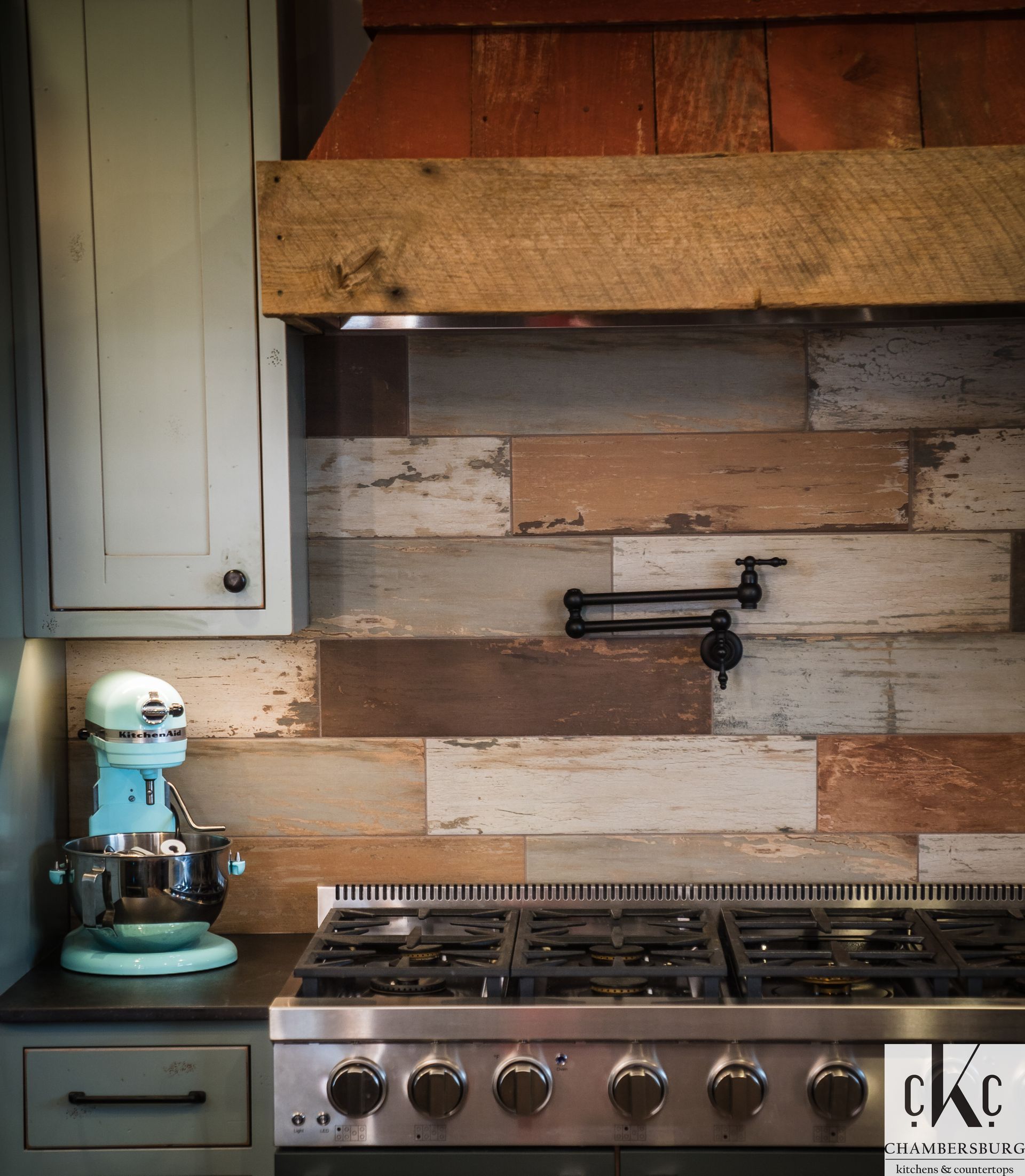 A kitchen with a stove top oven and a mixer on the counter.