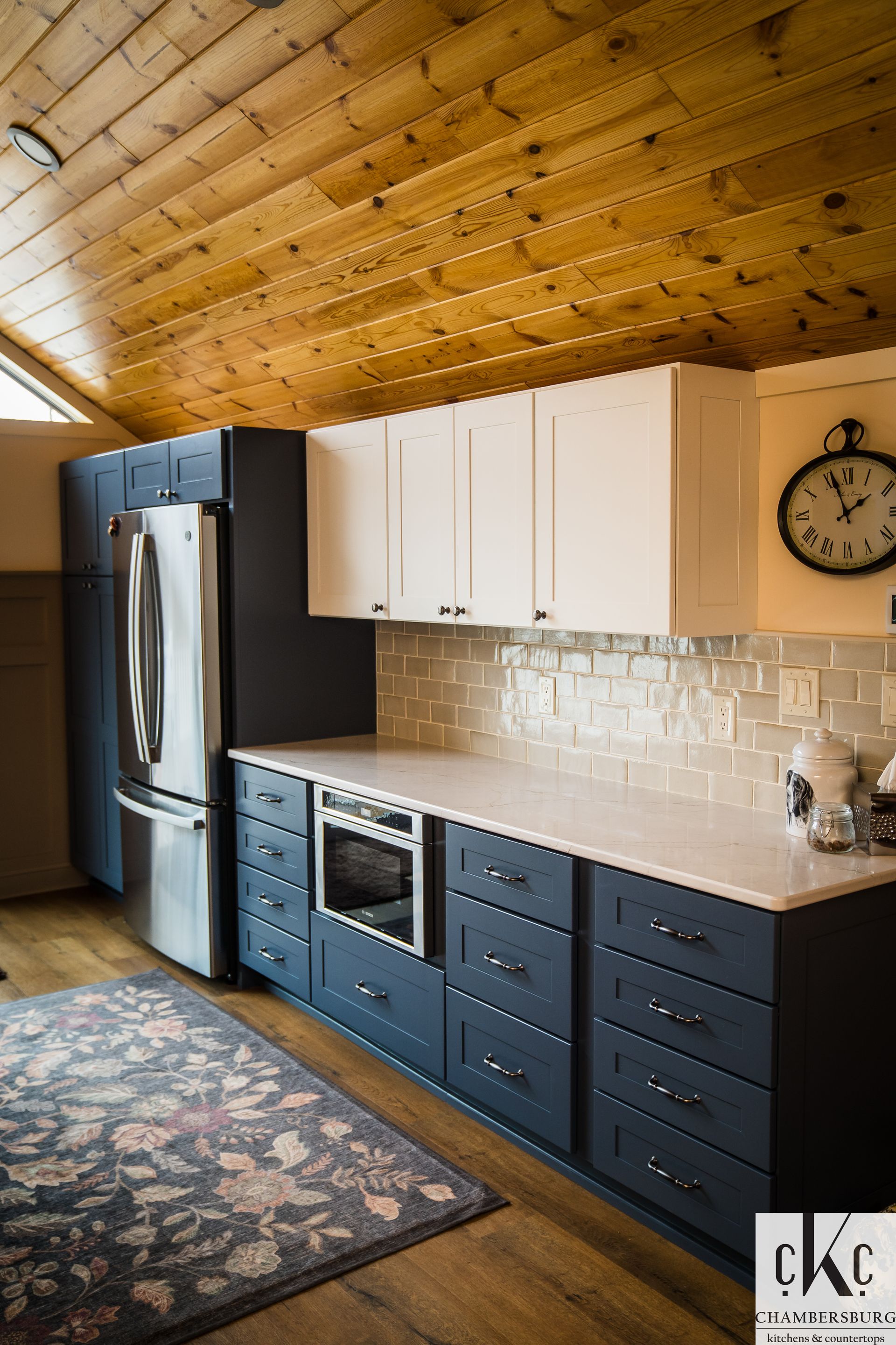 A kitchen with blue cabinets and white cabinets and a clock on the wall.
