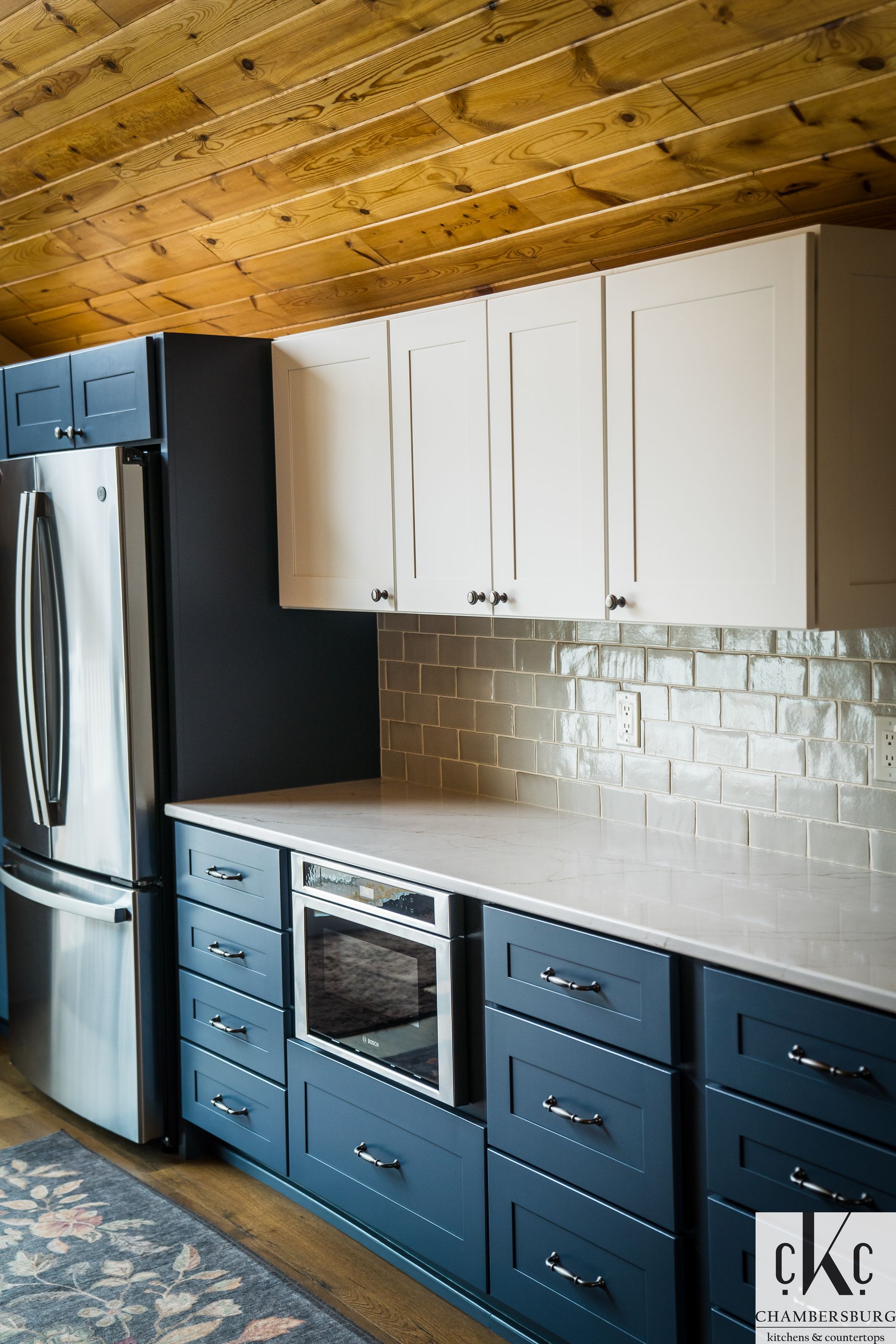 A kitchen with blue cabinets, white cabinets, stainless steel appliances and a refrigerator.