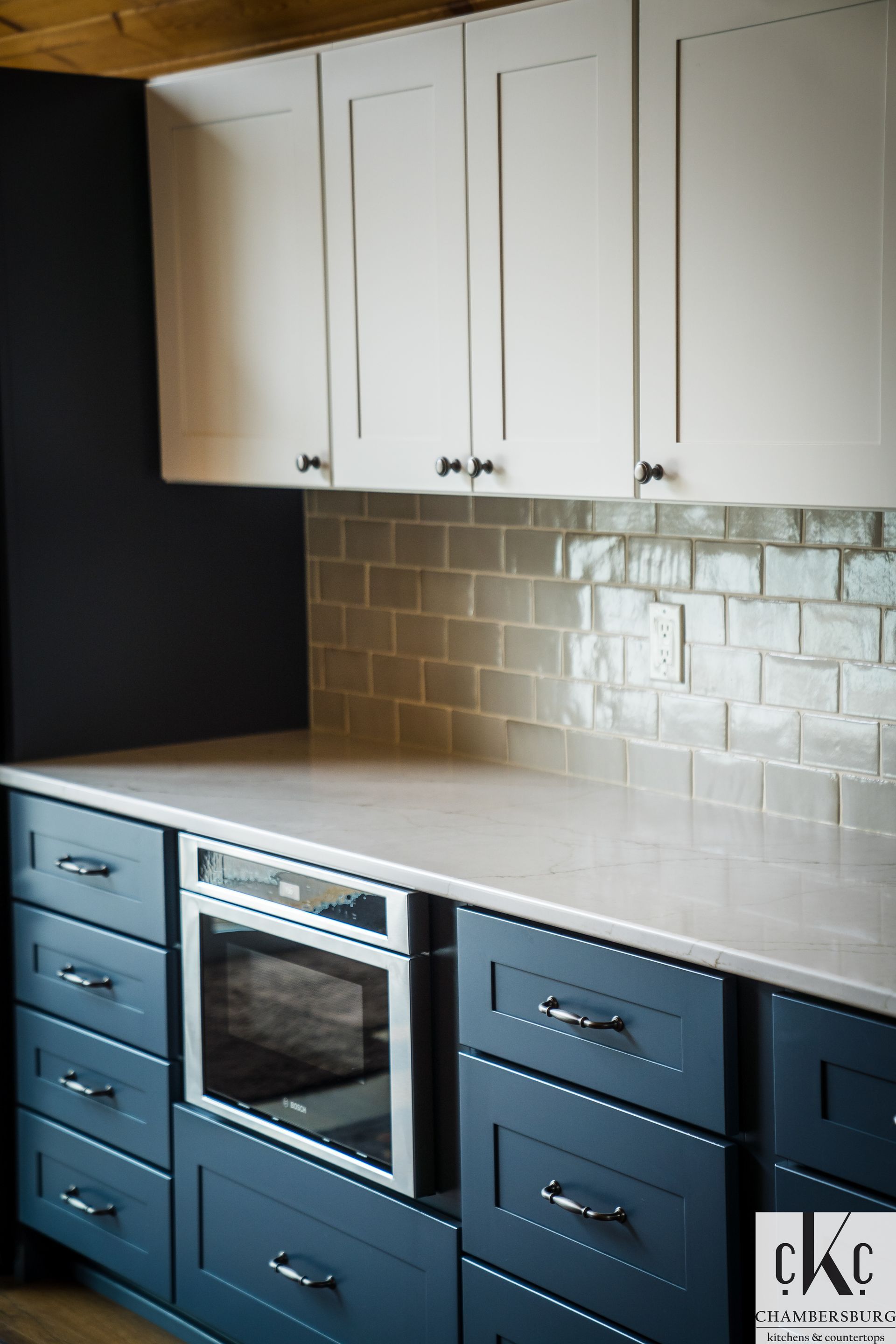 A kitchen with blue and white cabinets and a stainless steel oven