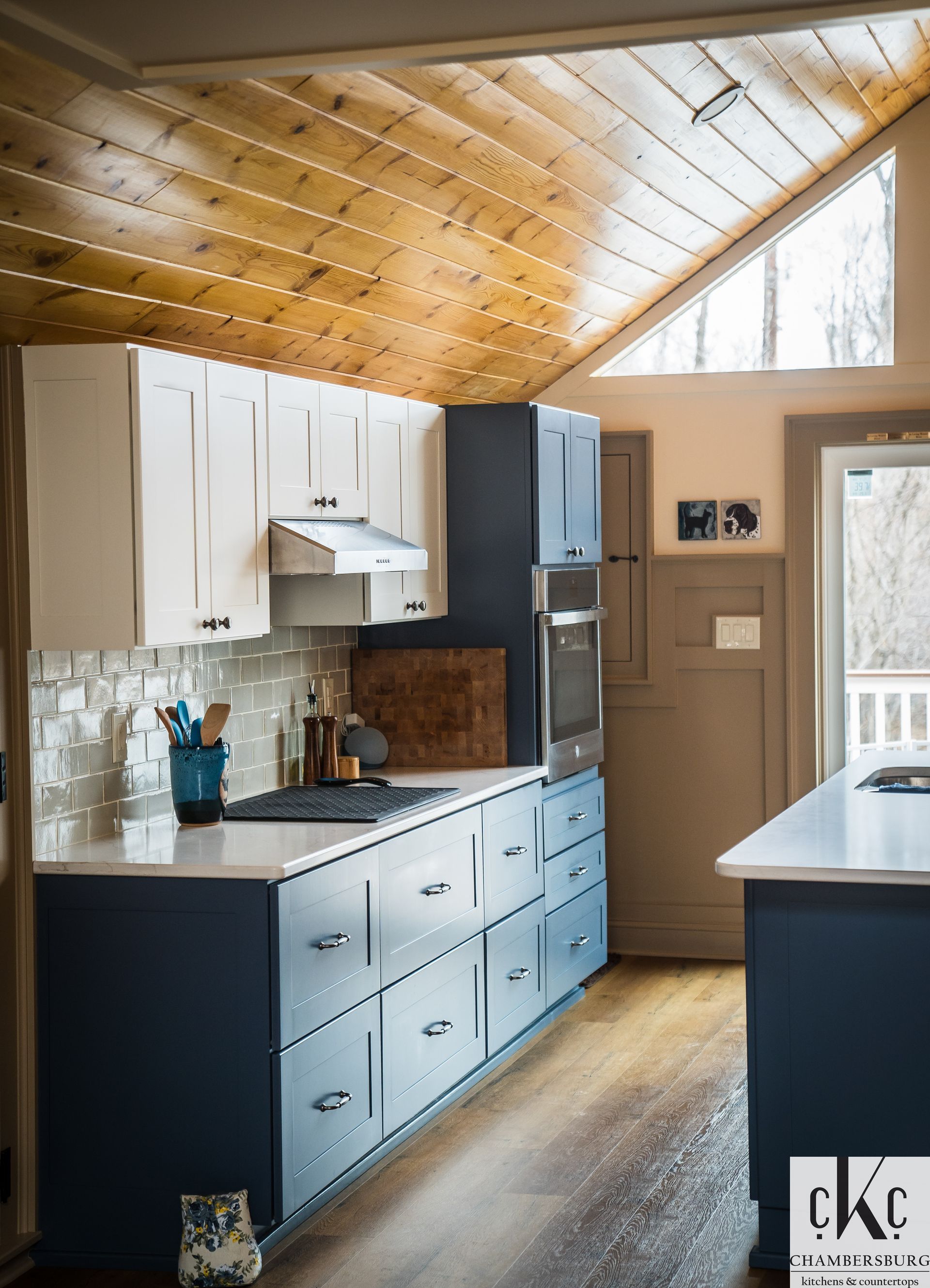 A kitchen with blue cabinets and a wooden ceiling.