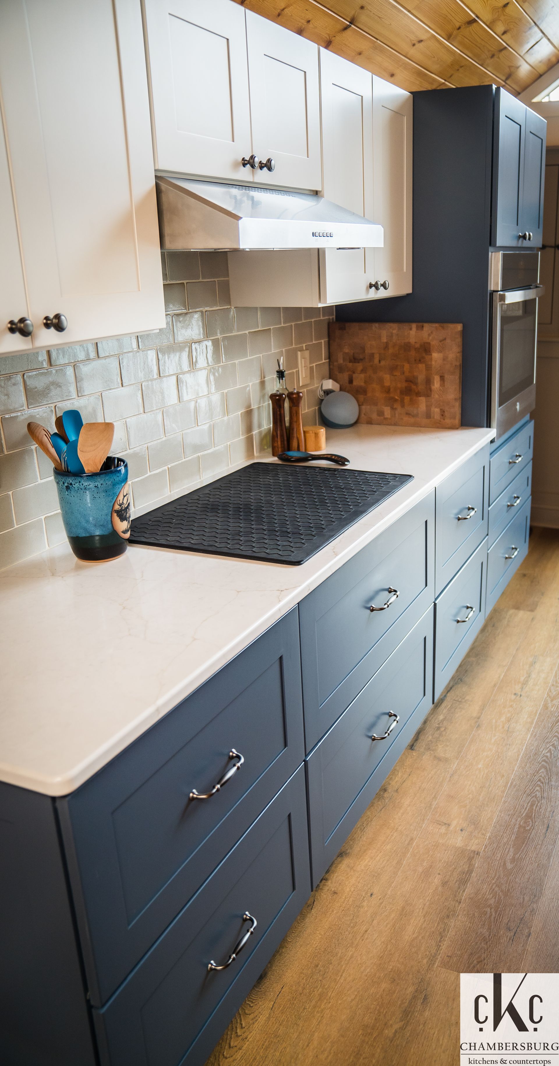 A kitchen with blue cabinets and white counter tops and a stove top oven.