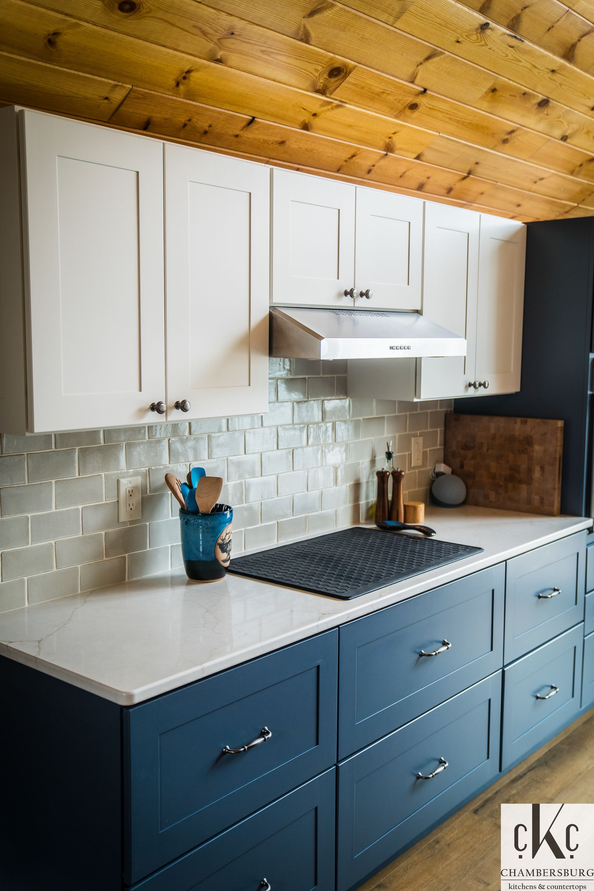 A kitchen with blue cabinets and white cabinets and a stove top oven.