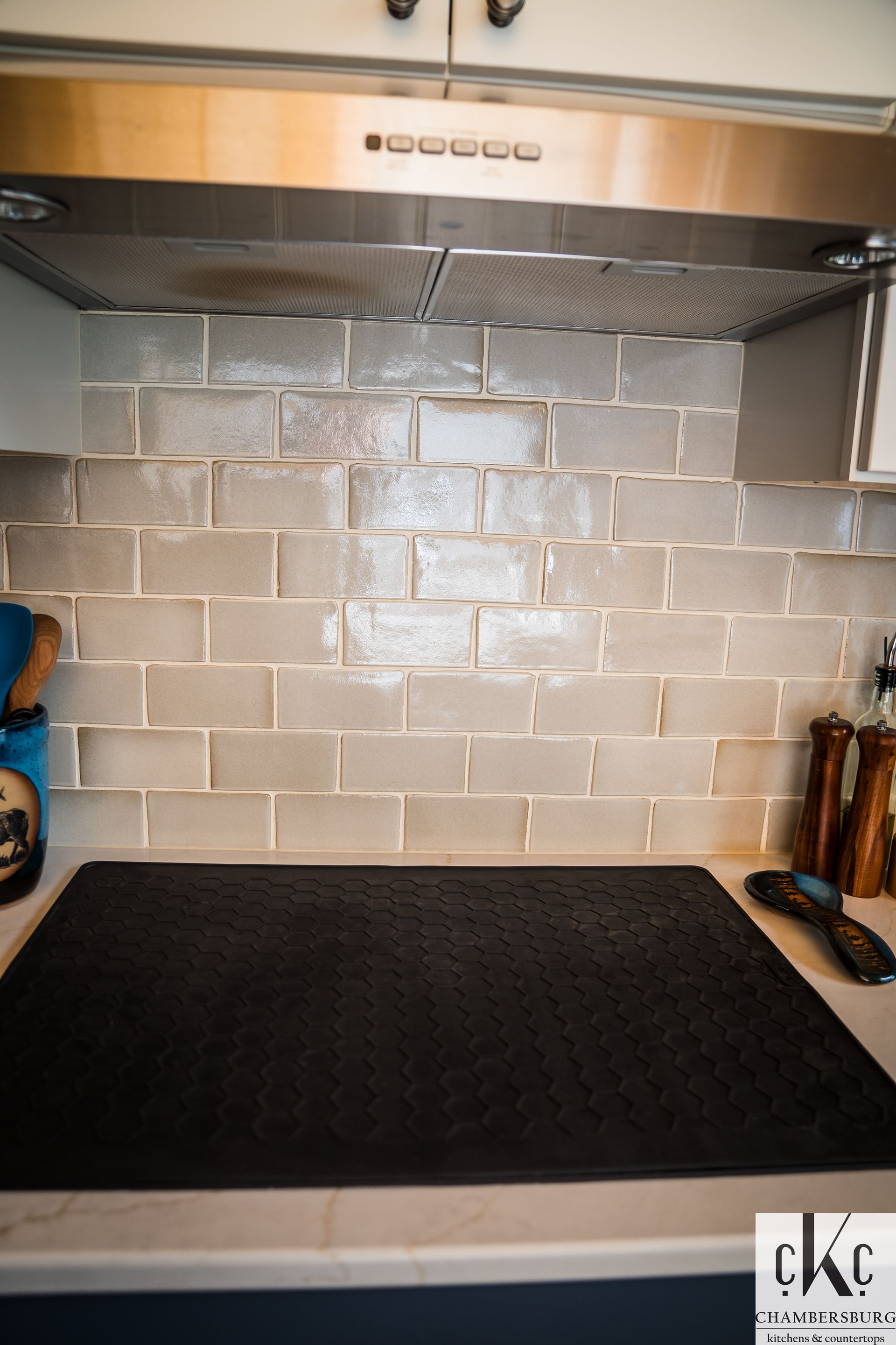 A kitchen with a stove top oven and a stainless steel hood.