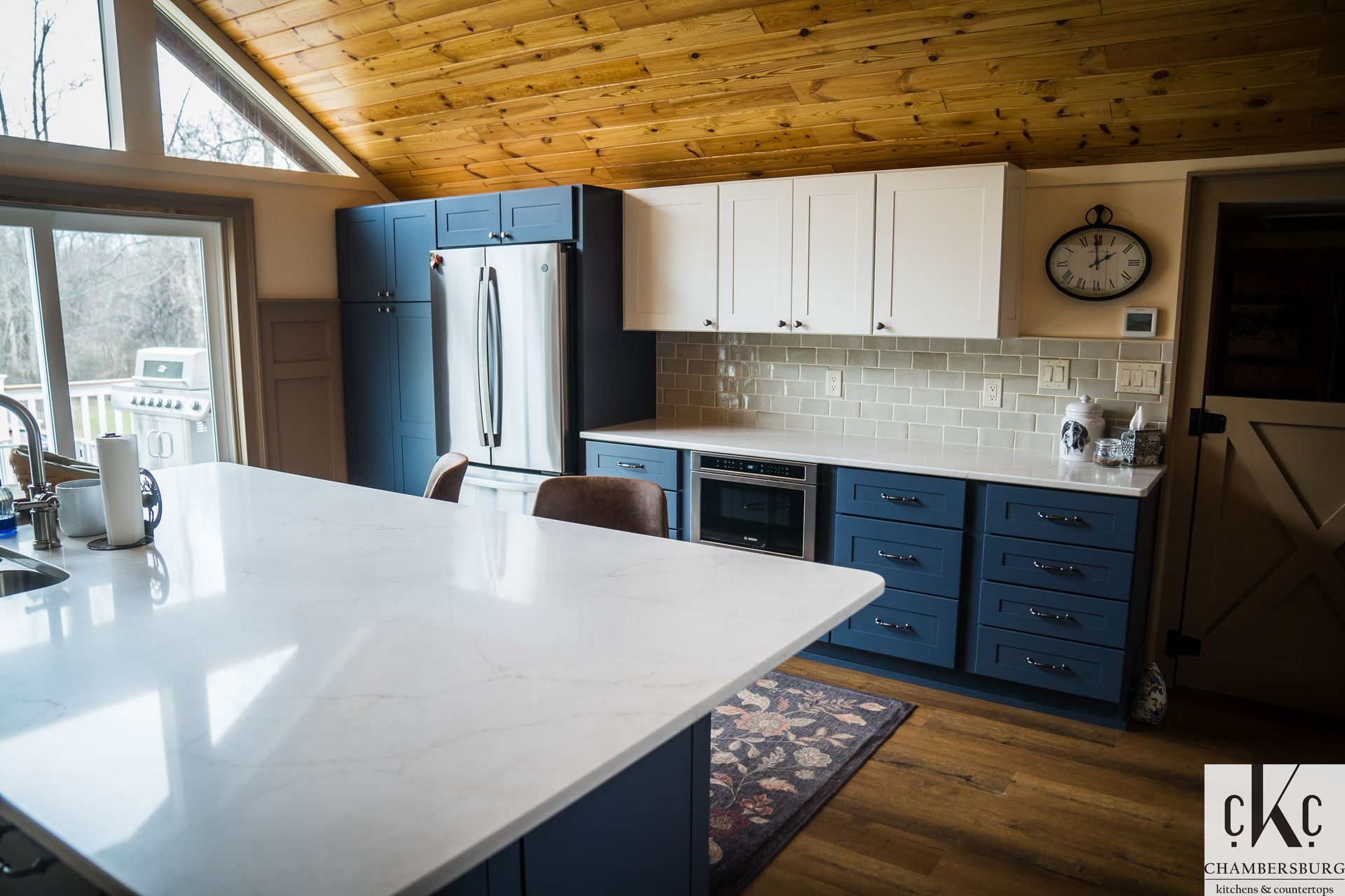 A kitchen with blue cabinets and white counter tops and a clock on the wall.