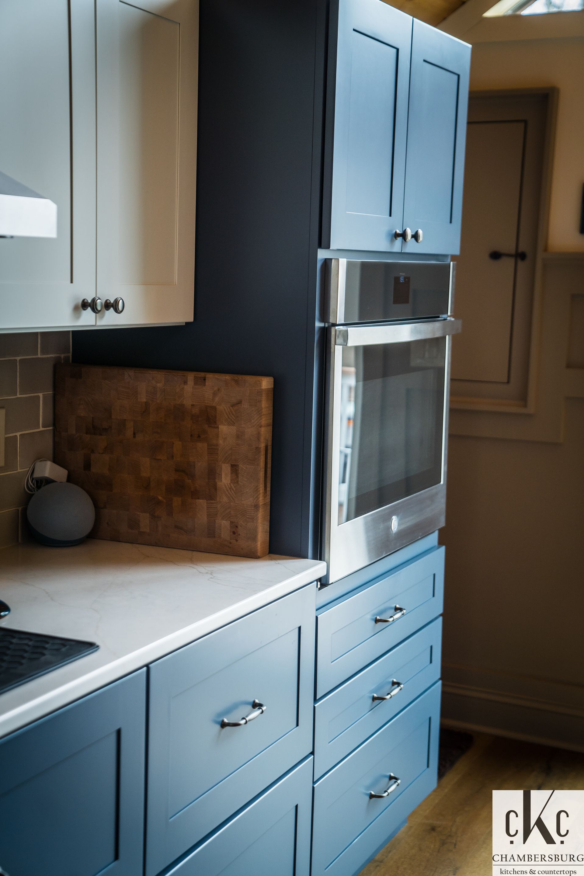 A kitchen with blue cabinets and a stainless steel oven
