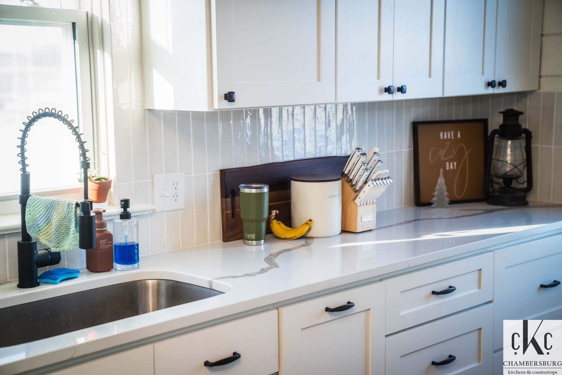 A kitchen with white cabinets and a stainless steel sink.