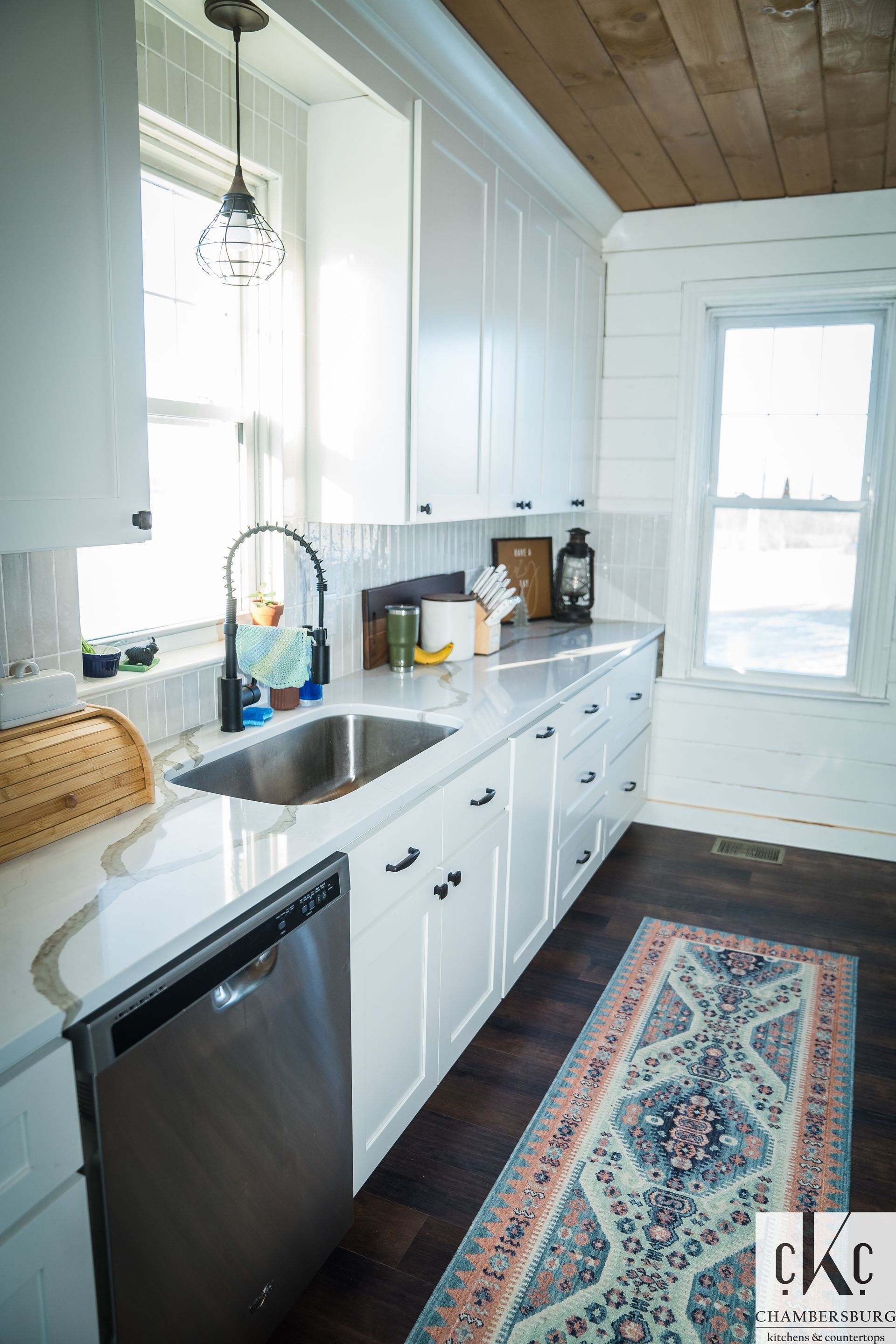 A kitchen with white cabinets, a sink, a dishwasher, and a rug.