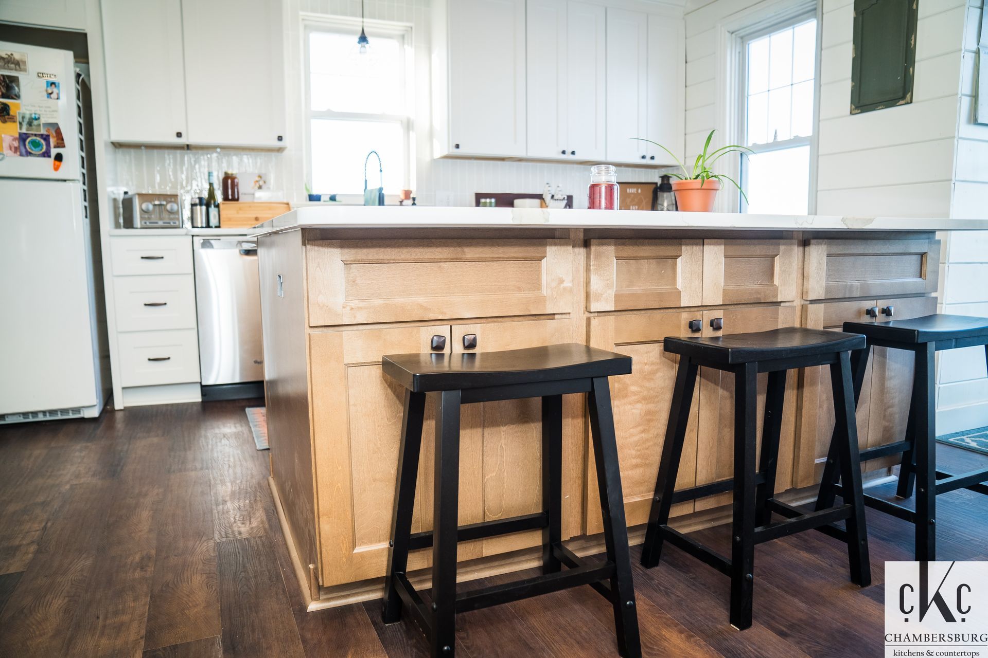 A kitchen with wooden cabinets and black stools