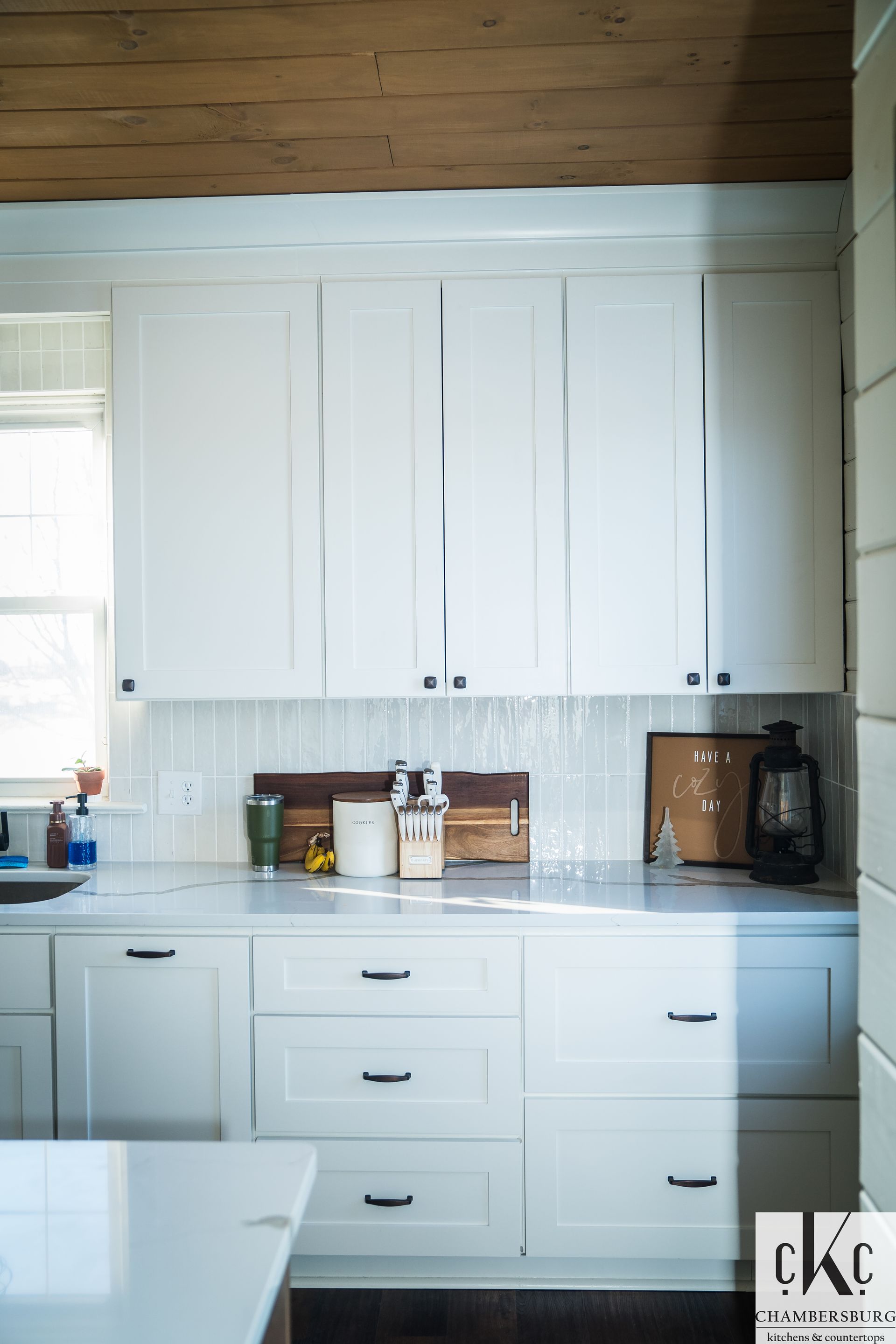 A kitchen with white cabinets and a wooden ceiling
