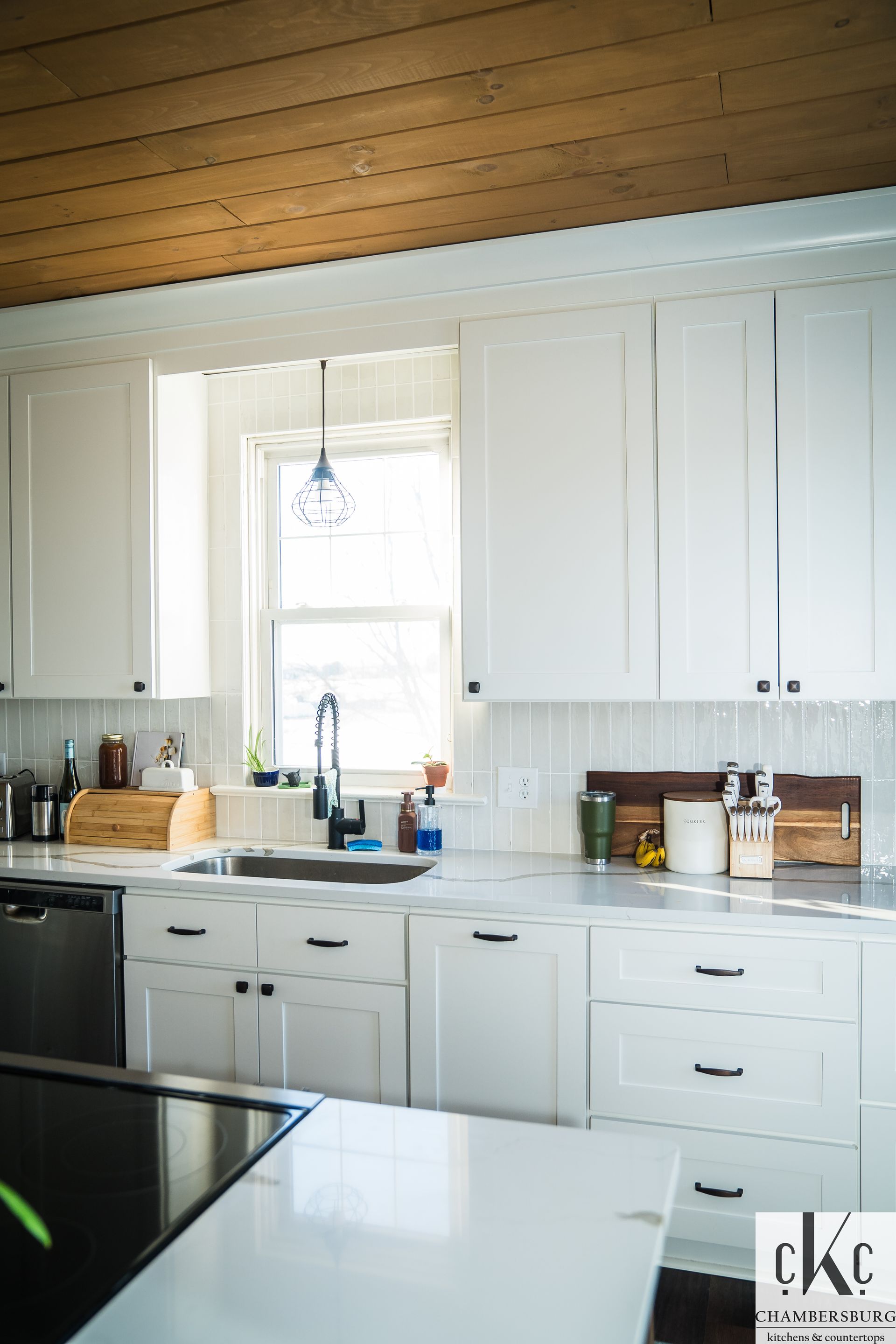 A kitchen with white cabinets, a sink, and a window.