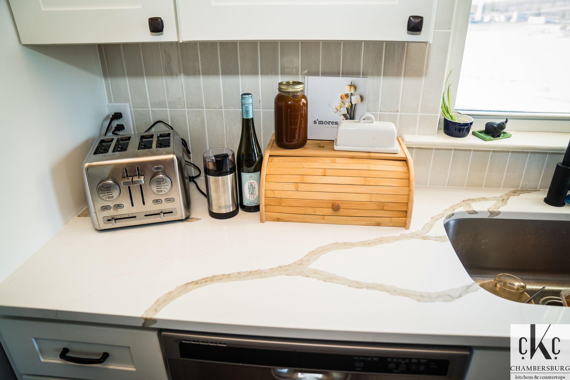 A kitchen counter with a toaster and a bottle of wine on it.
