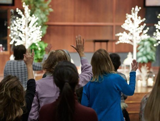 a man is raising his hand in the air at a church service .