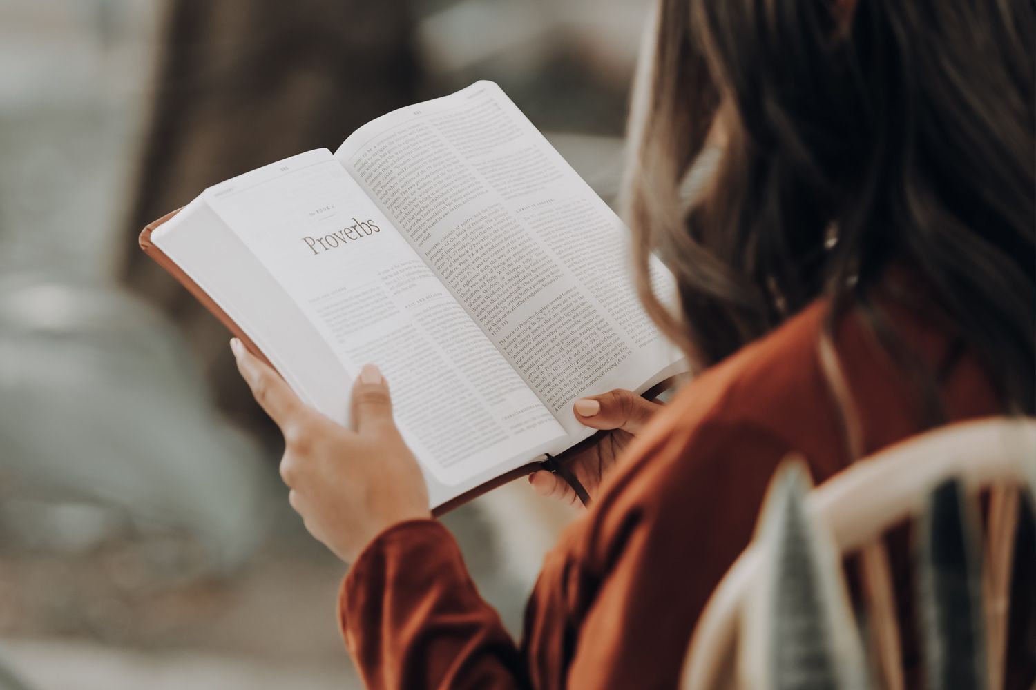 A woman is sitting in a chair reading a book.