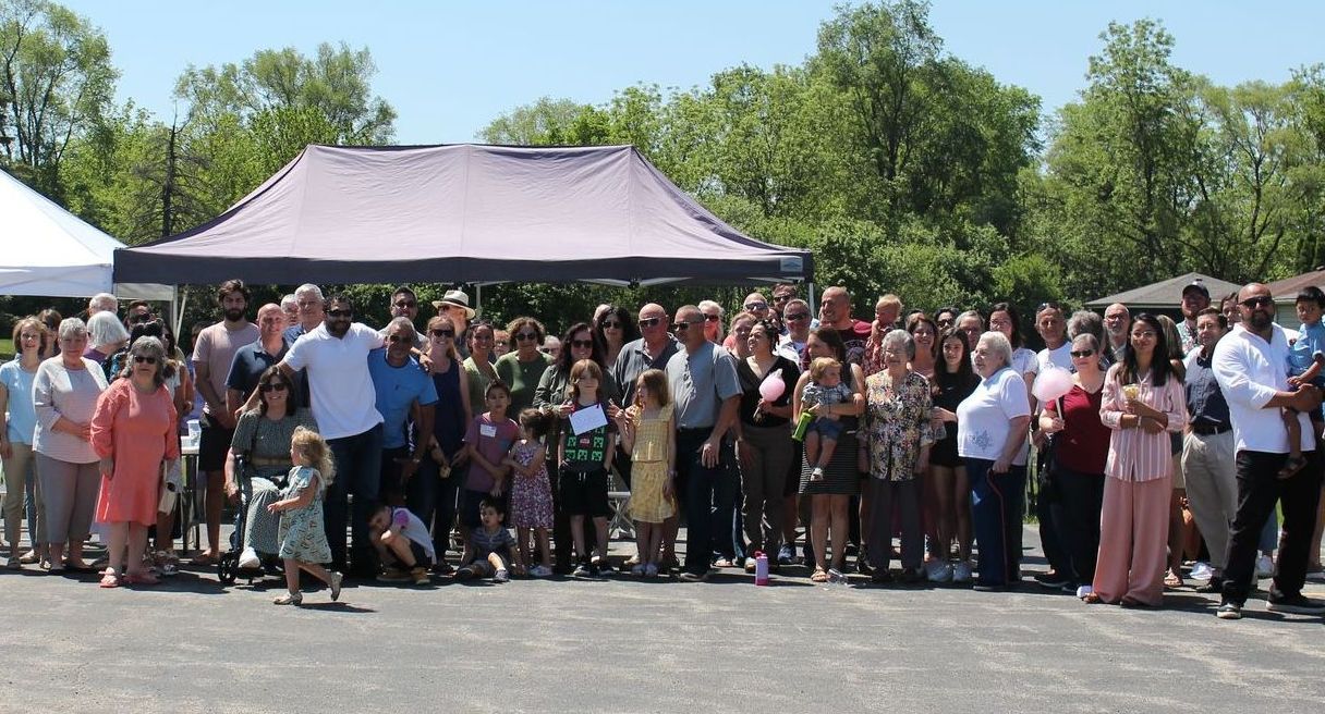 A large group of people are standing in front of a tent Itasca Church picnic volunteer opportunity