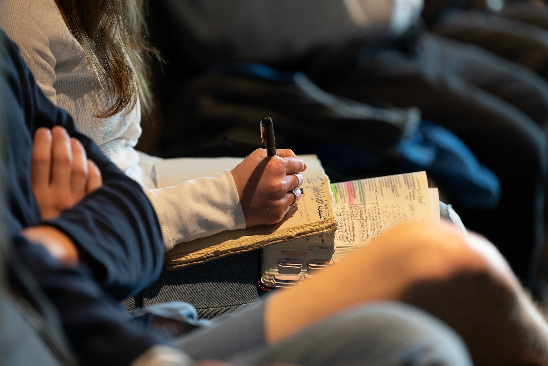 a person is writing in a bible while sitting in a sermon at a bible based church