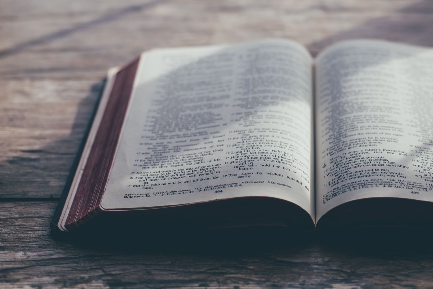 An open bible is sitting on a wooden table.