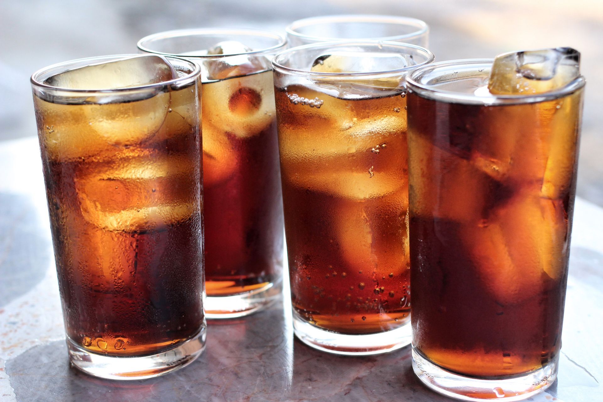 Four glasses of cola with ice cubes on a table
