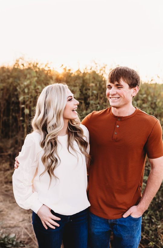 A man and a woman are standing next to each other in a field.