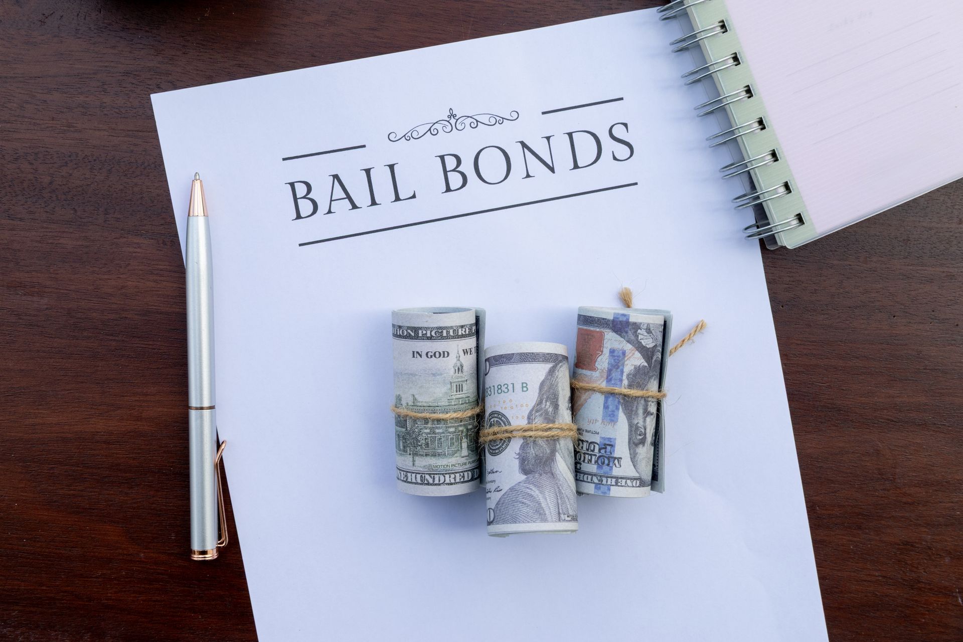 Bail bonds form with a pen and rolled cash on a desk.
