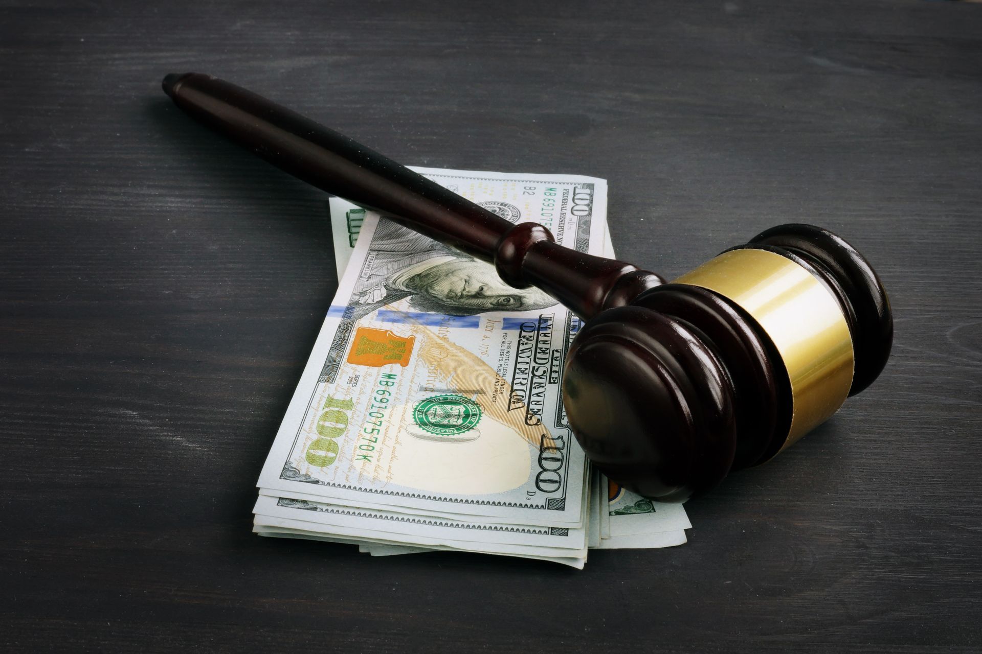 Judge's gavel resting on a stack of cash on a dark surface.