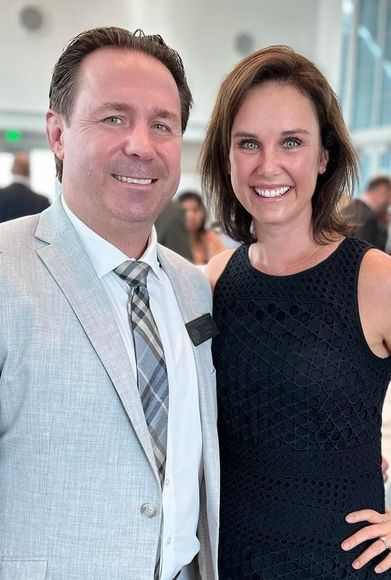 A man in a suit and tie is standing next to a woman in a black dress.