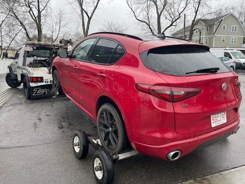 A red car is being towed by a tow truck.