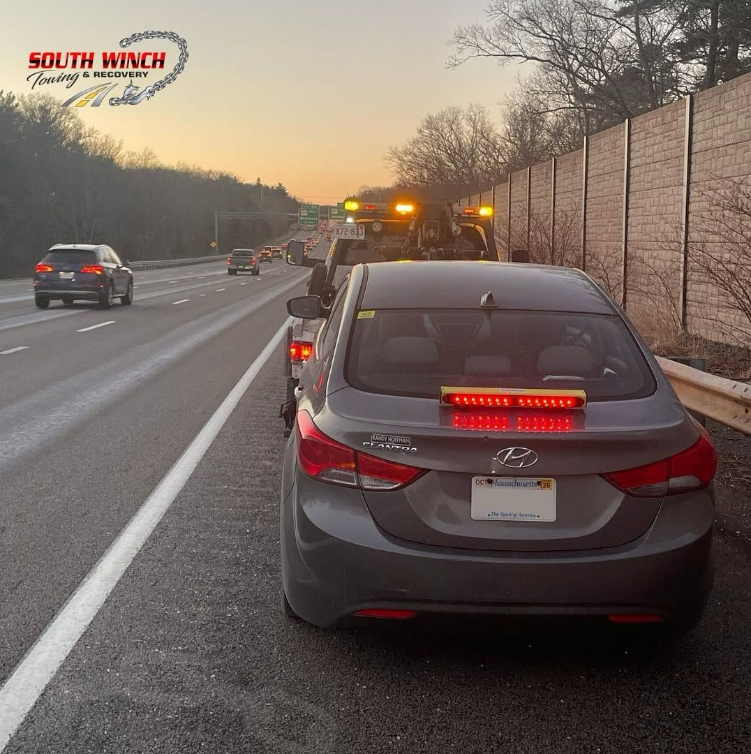 A car is being towed down a highway by south winch