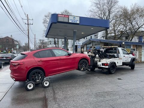 A red car is being towed by a white tow truck.