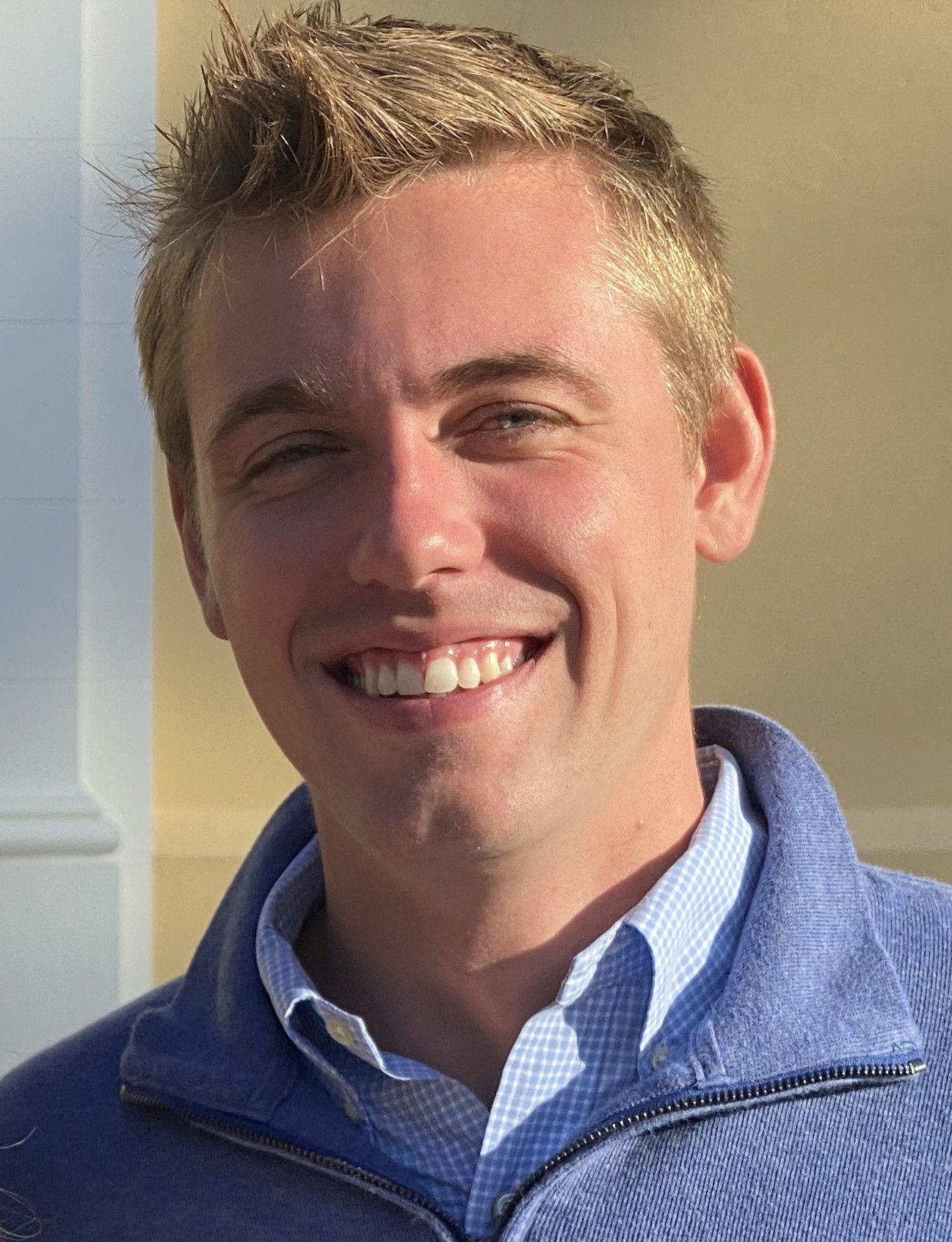 A man in a blue sweater is smiling for the camera.