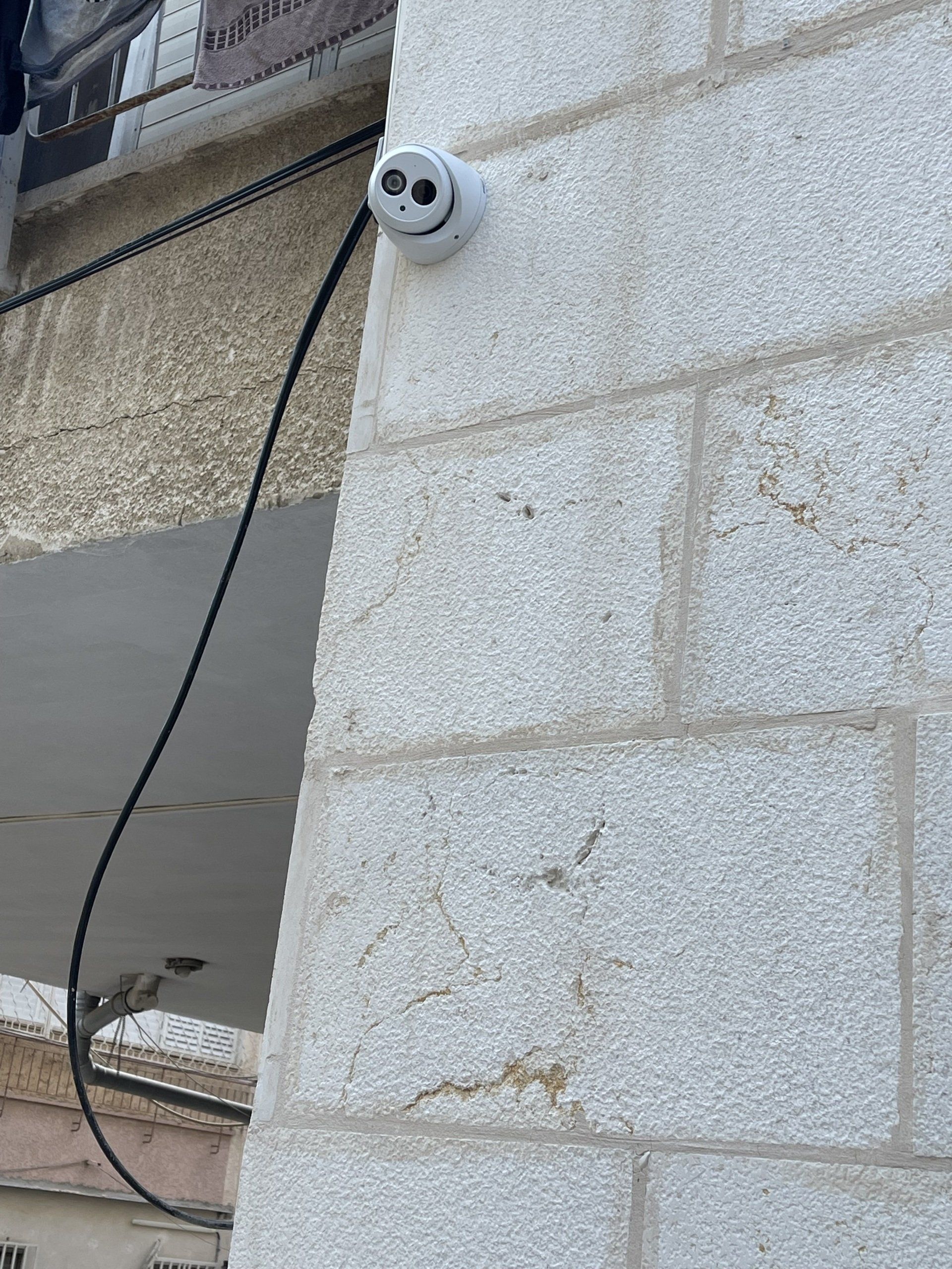 מצלמה מותקנת בצד של בניין לבנים.