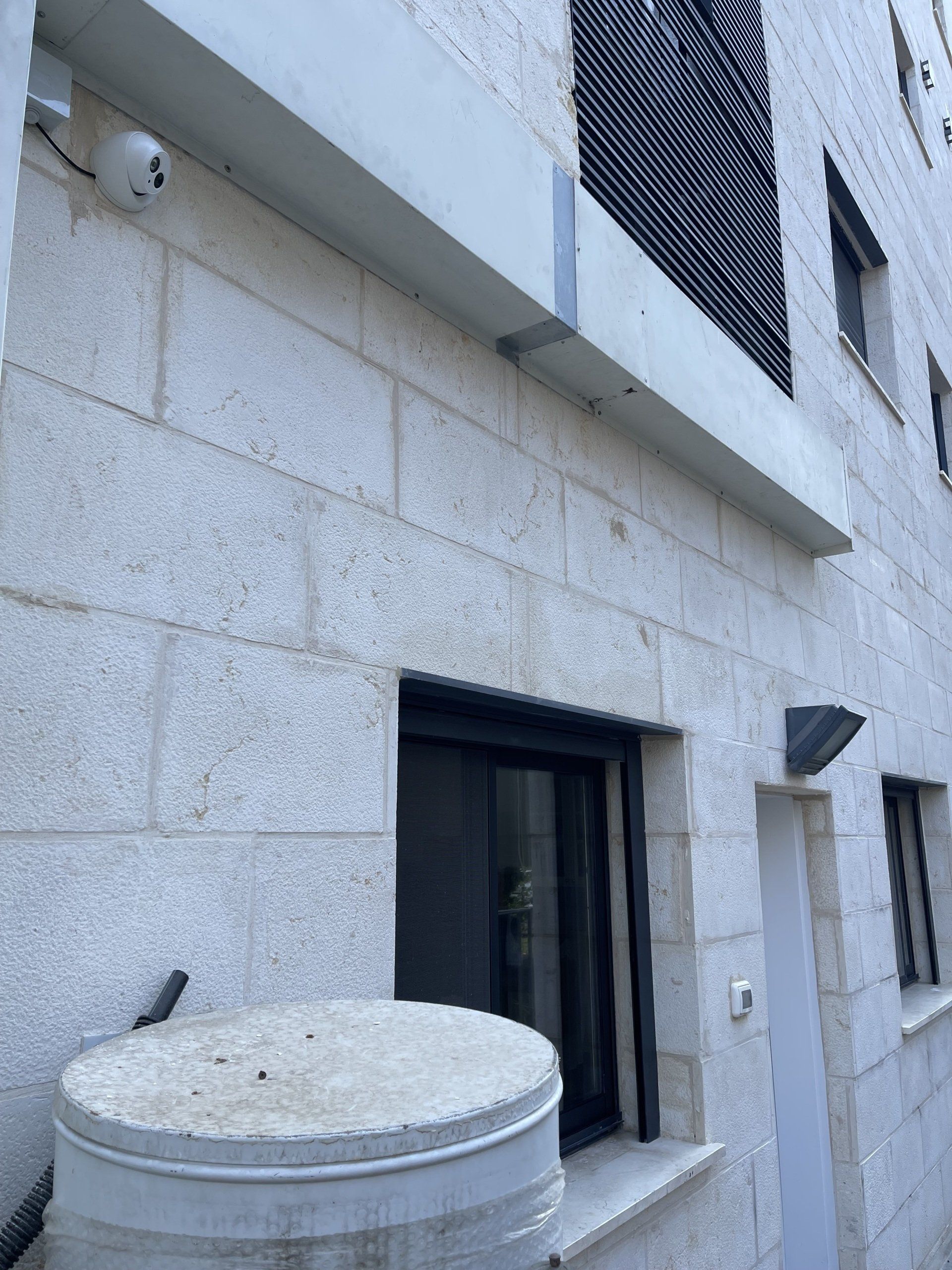 בניין לבנים עם חלון ודלי לפניו