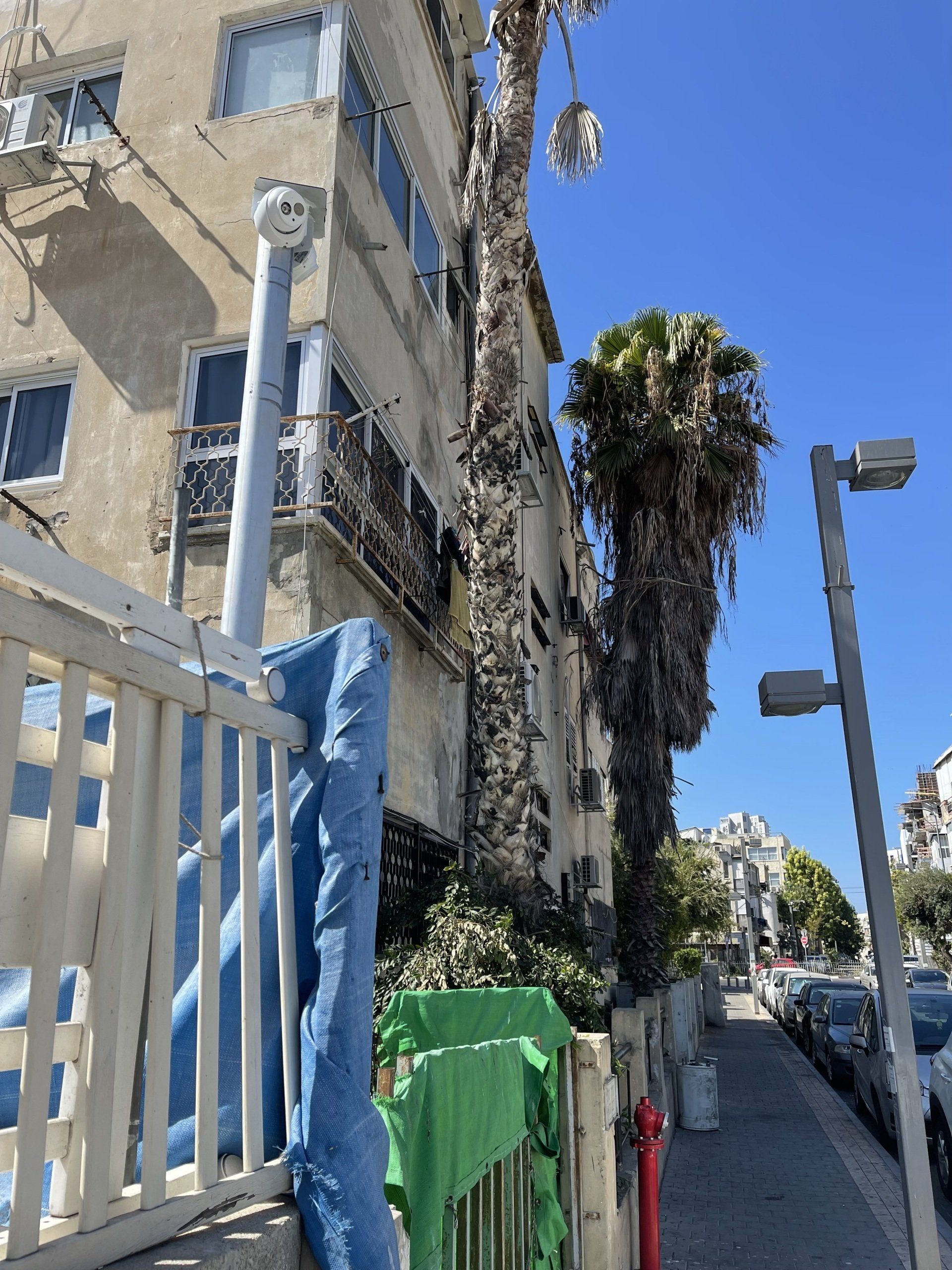 שורת מכוניות חונות על מדרכה מול בניין