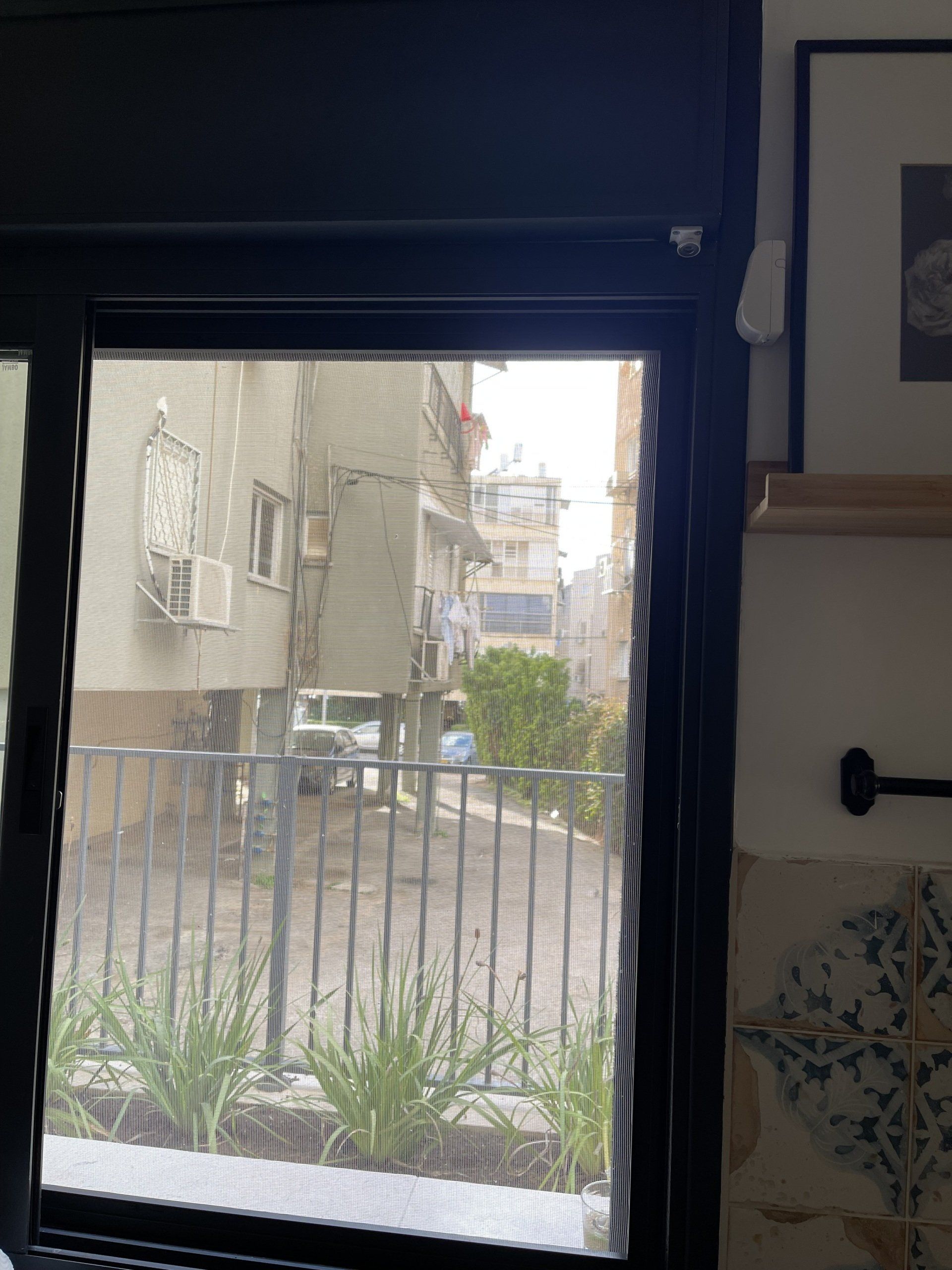 חלון עם גדר ברקע ותמונה על הקיר.