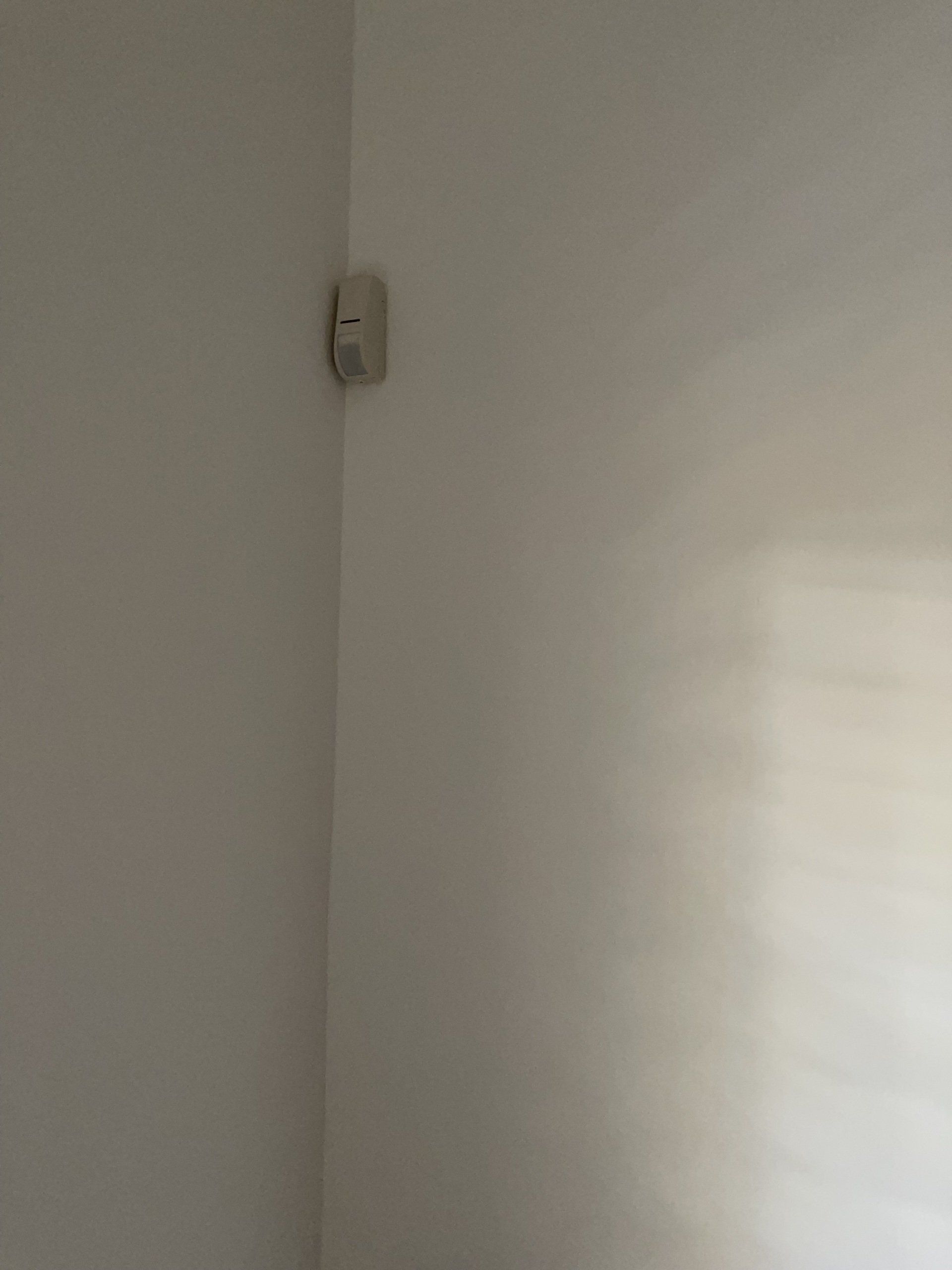 קיר לבן ועליו חפץ לבן בפינת החדר.