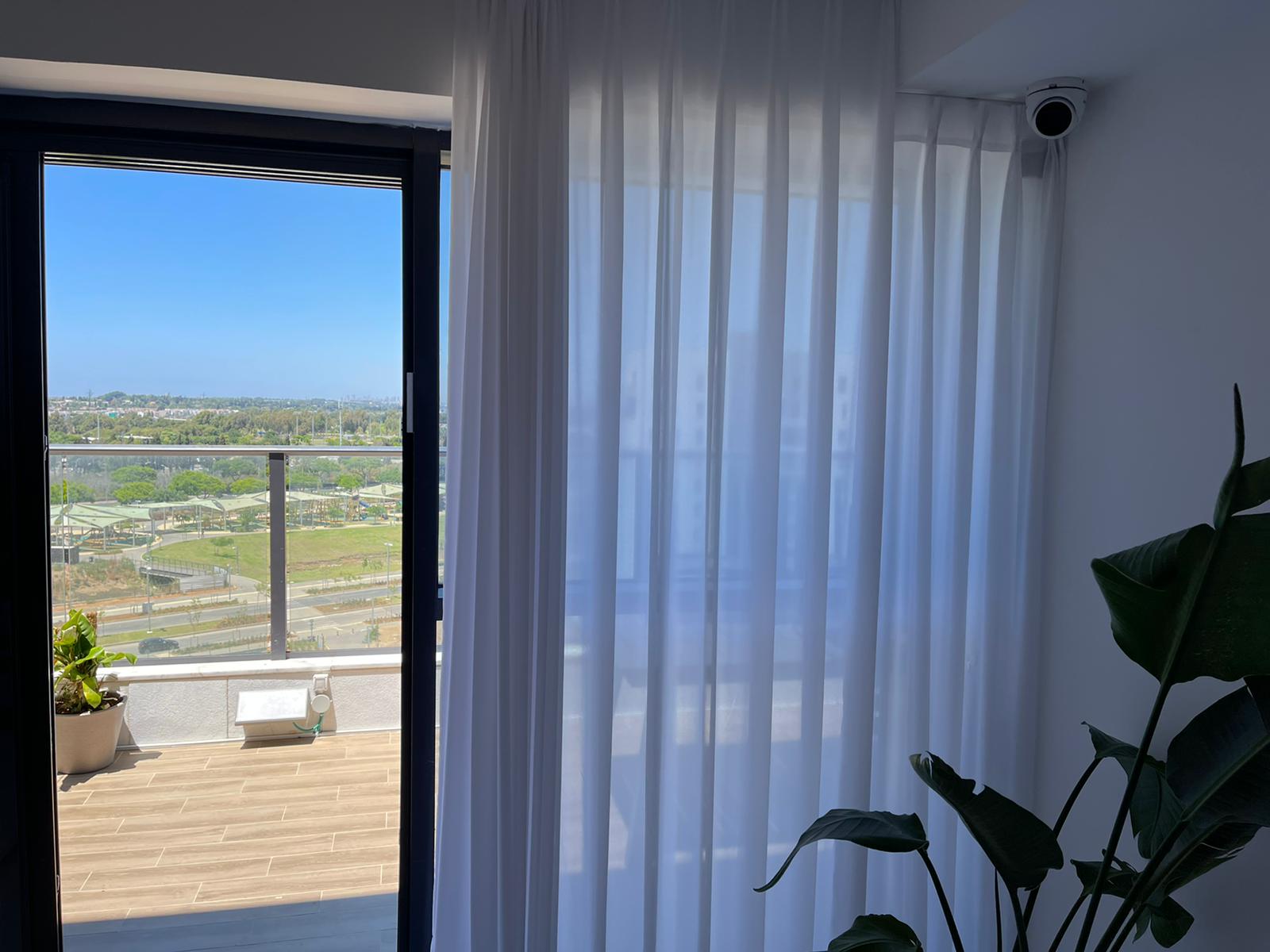 סלון עם וילונות לבנים ונוף למרפסת.