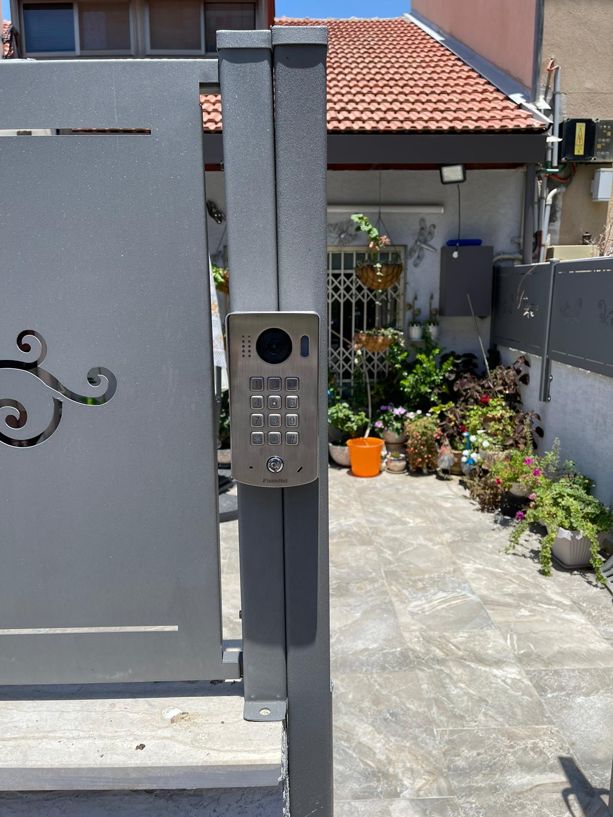 שער שעליו לוח מקשים ובית ברקע