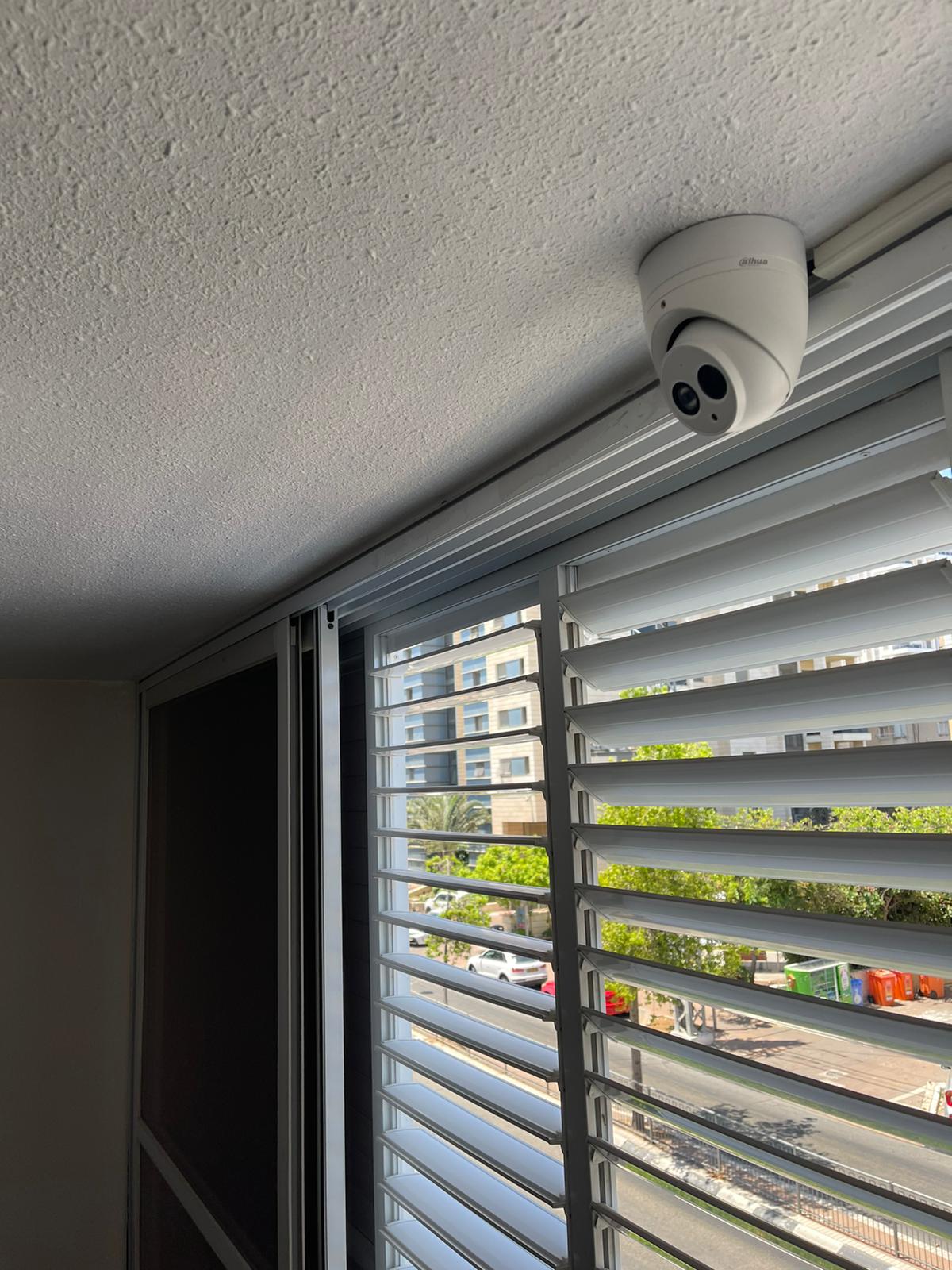 מצלמה מותקנת על התקרה מעל חלון עם תריסים.