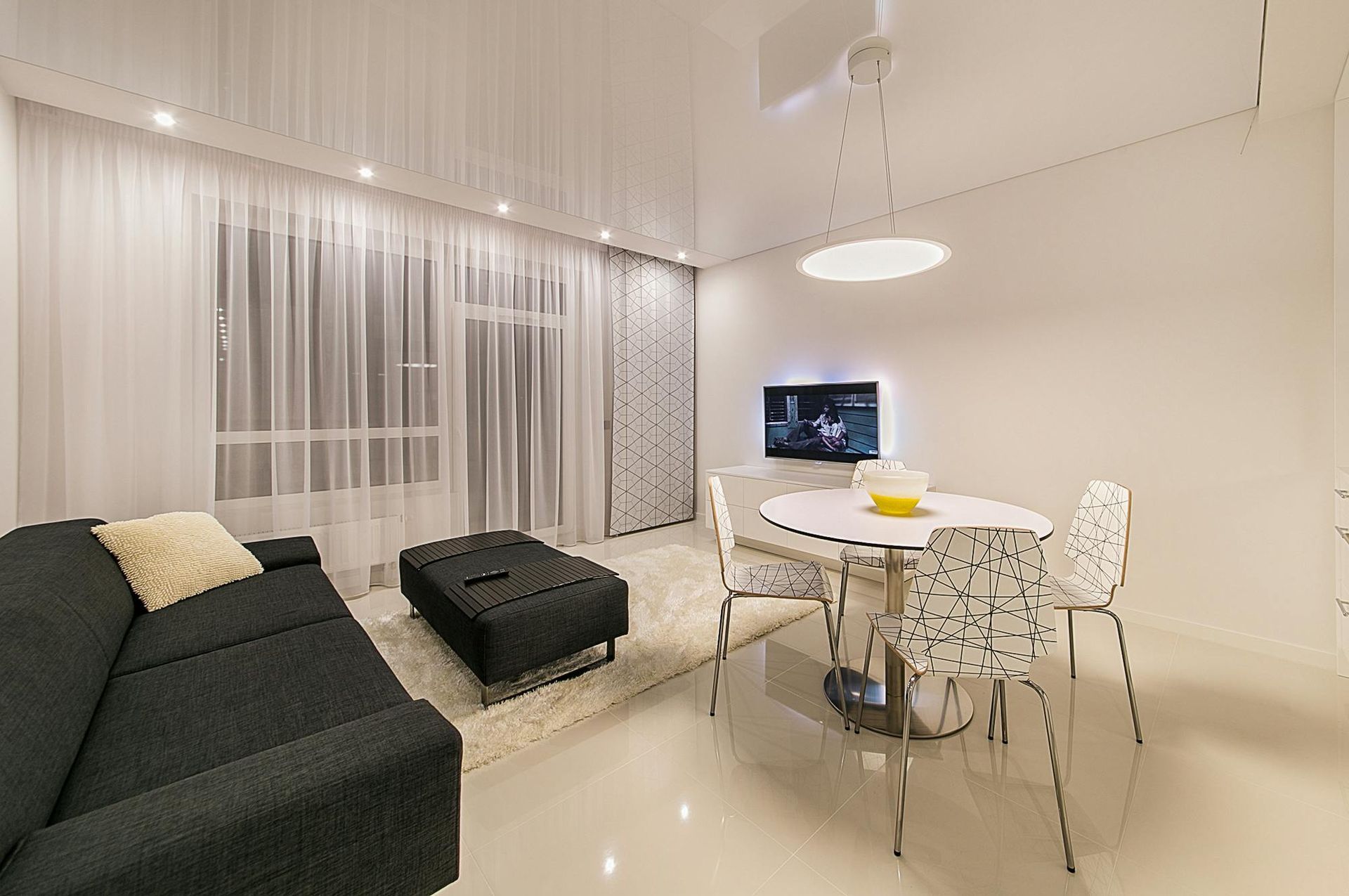 A living room with a couch , table and chairs and a flat screen tv.