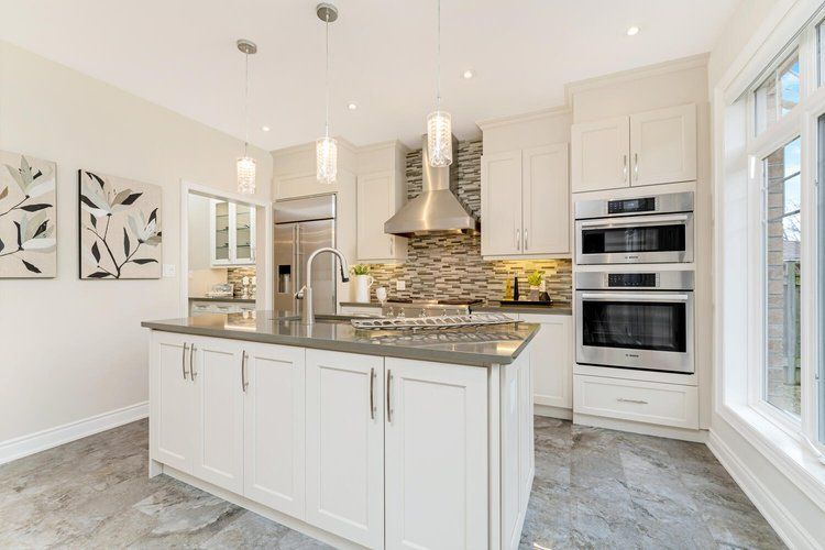 A kitchen with white cabinets , stainless steel appliances , and a large island.