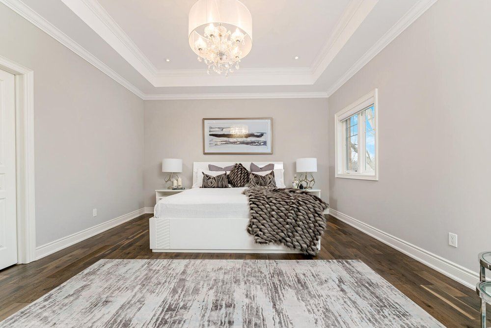 A bedroom with a bed , rug , lamps and a chandelier.