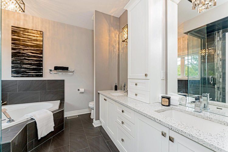 A bathroom with two sinks , a tub and a mirror.