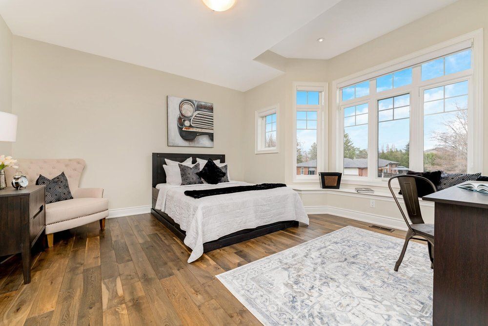 A bedroom with a bed , chair , desk and windows.